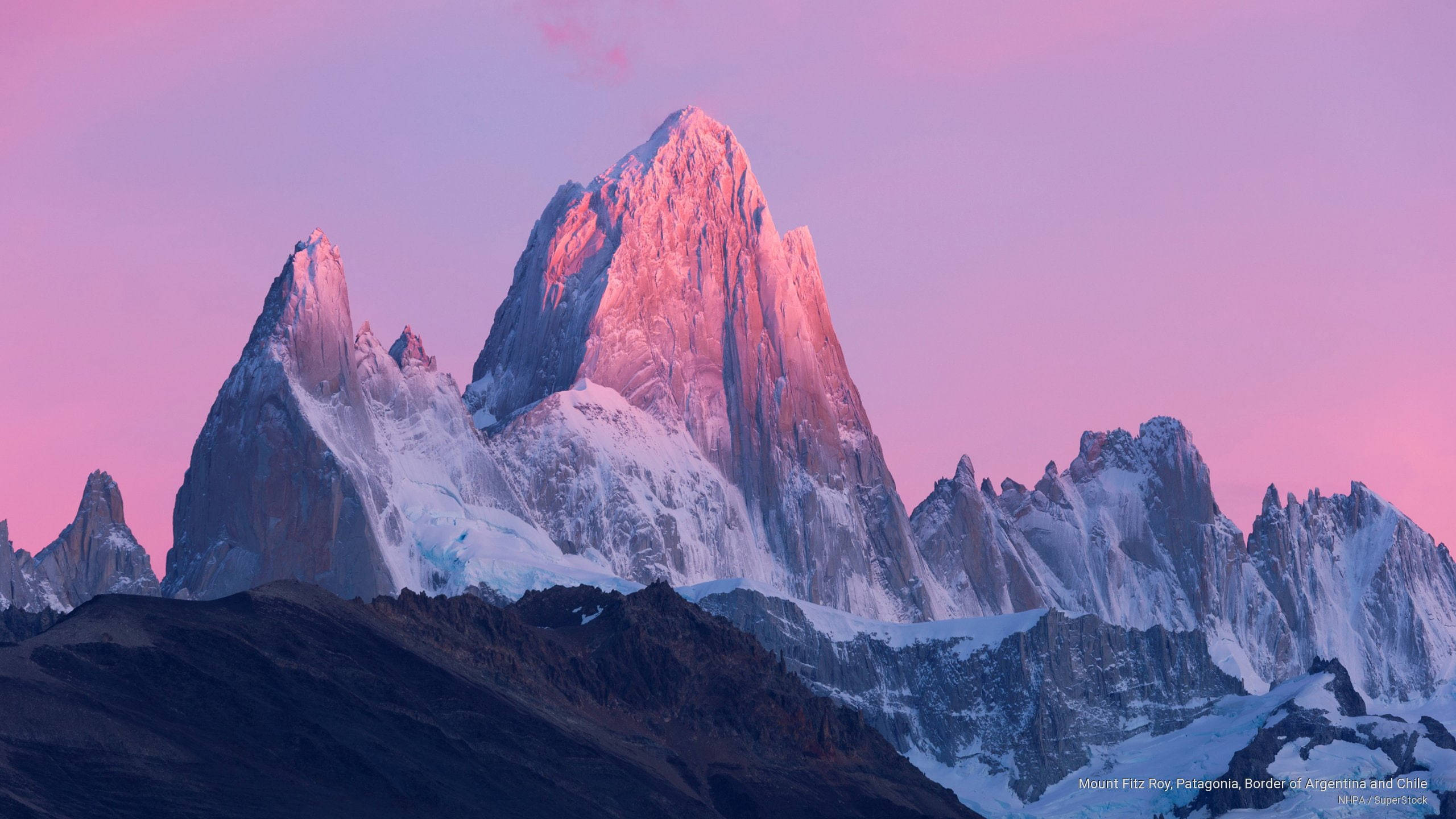 Patagonia 桌布 壁紙 — 巴塔哥尼亞柔和暮色中，菲茨羅伊山白雪覆蓋的鋸齒狀山峰閃耀著粉紅和金色。