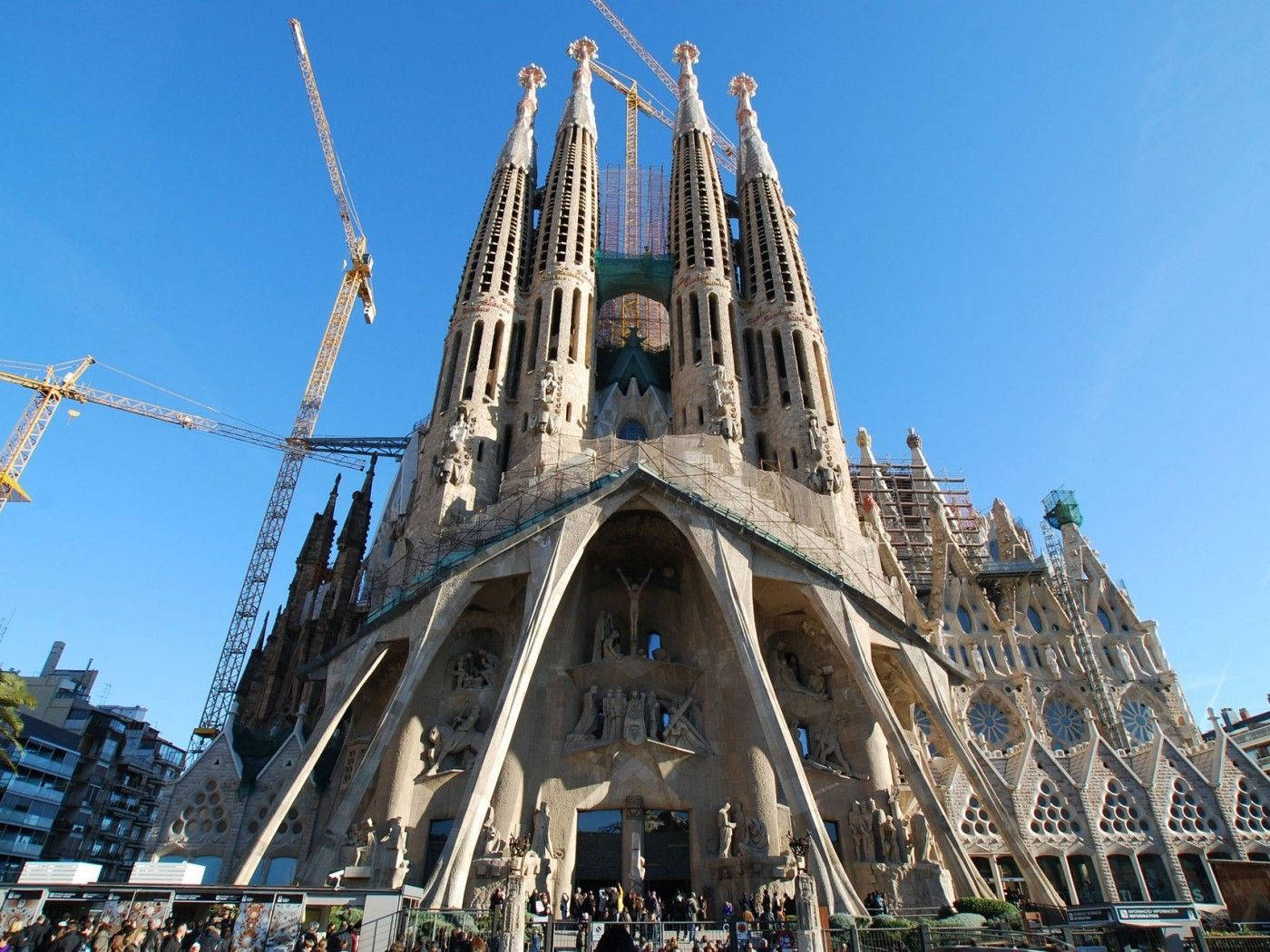 Barcelona 桌布 壁紙 — 巴塞隆納藍天下宏偉的聖家堂大教堂，底部有起重機和人群。