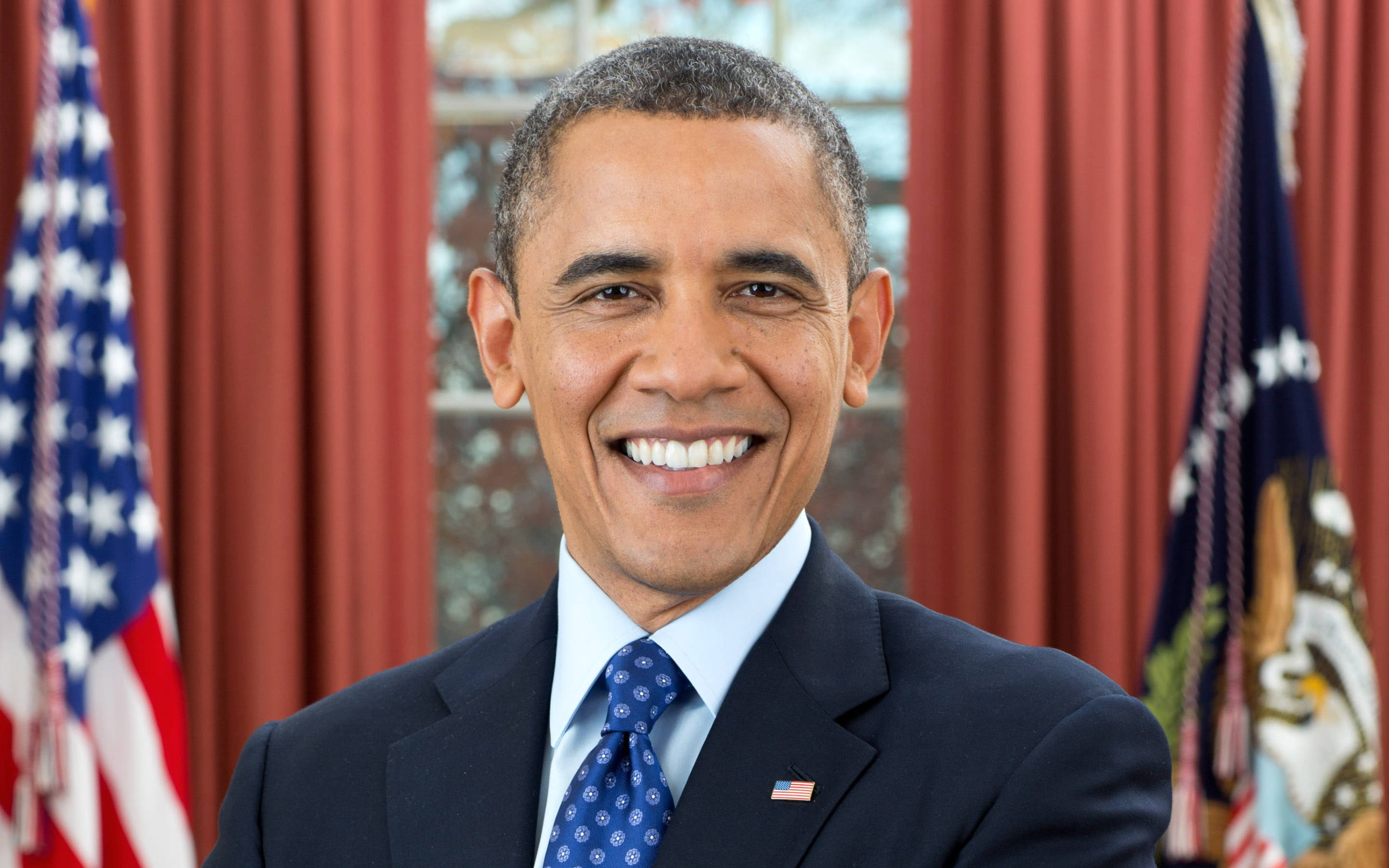 Barack 桌布 壁紙 — 巴拉克·歐巴馬在正式肖像中溫暖微笑，身穿深色西裝配藍色領帶，身後有美國國旗。