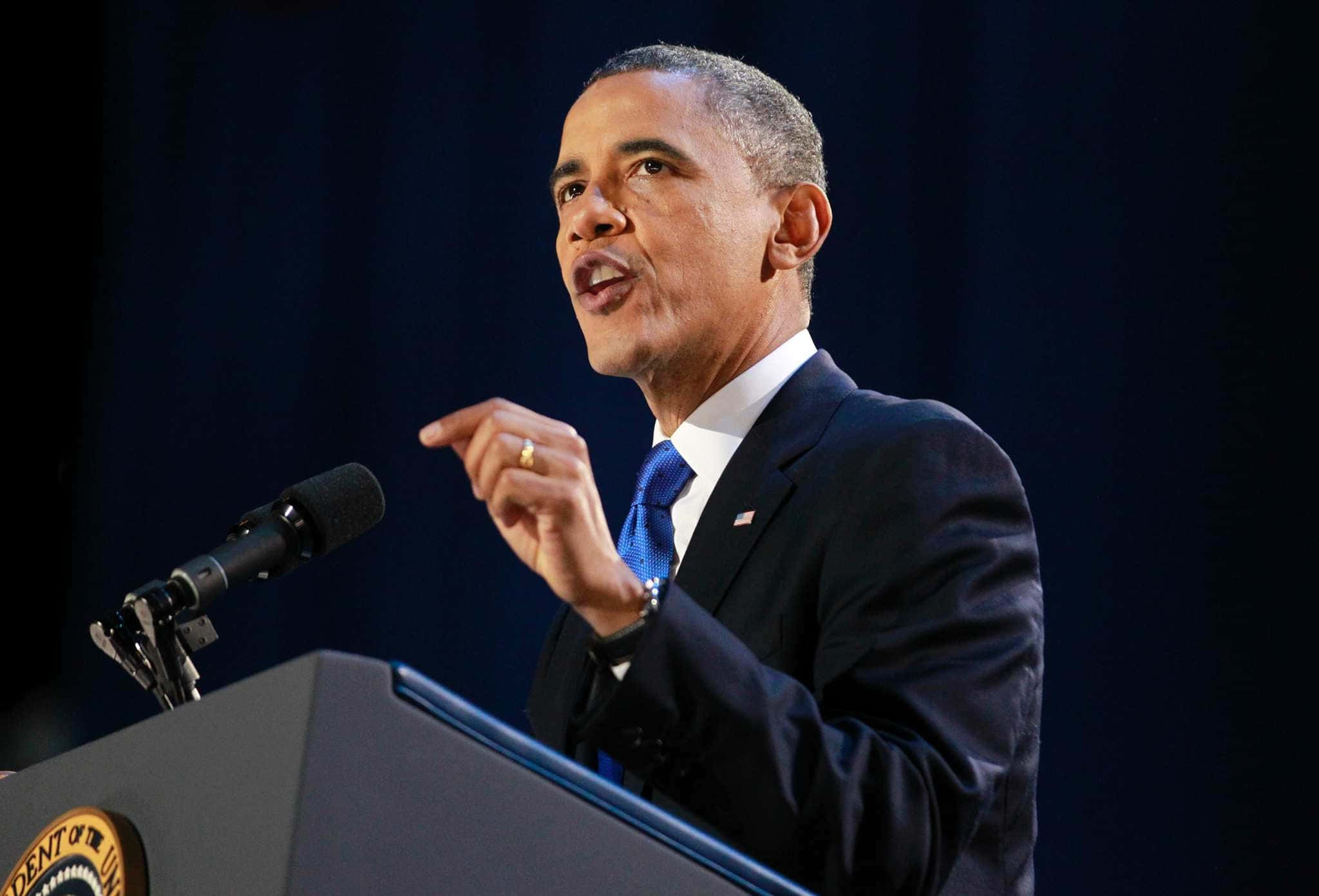 Barack Obama 桌布 壁紙 — 巴拉克·歐巴馬在深藍色窗簾背景下，穿著西裝和藍色領帶，在講台上熱情演講。