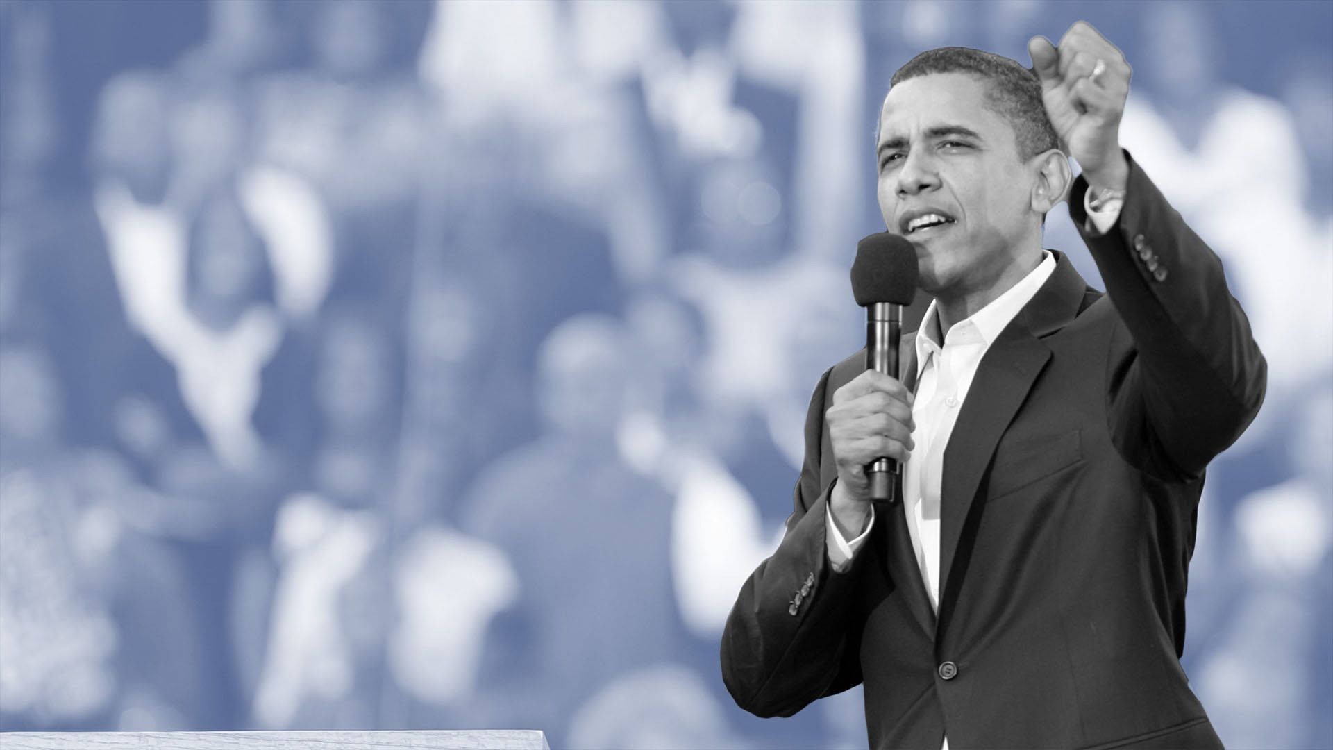 Barack 桌布 壁紙 — 巴拉克·歐巴馬在藍色調的模糊人群前，舉起拳頭熱情地對著麥克風講話。