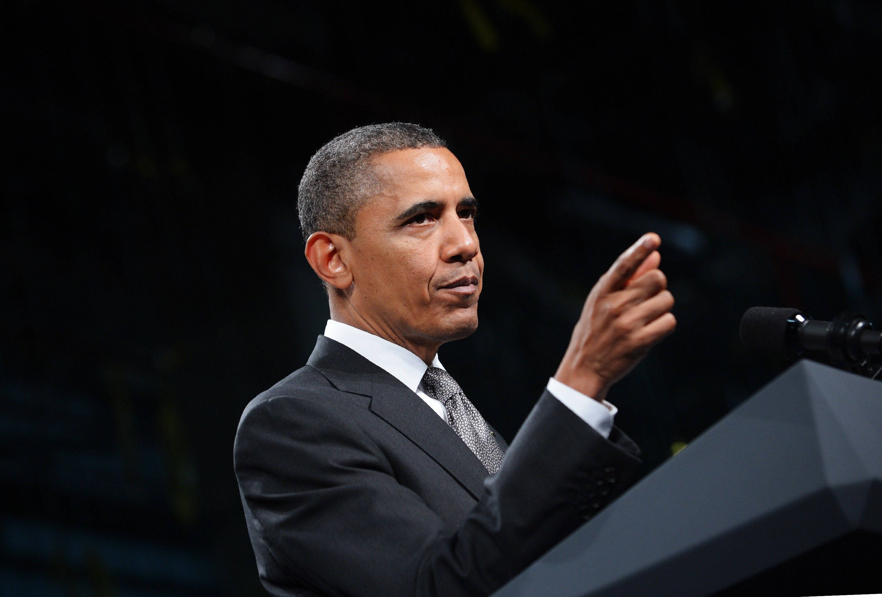Barack 桌布 壁紙 — 巴拉克·歐巴馬在講台上熱情演講，黑暗模糊的背景強調了他專注的表情。