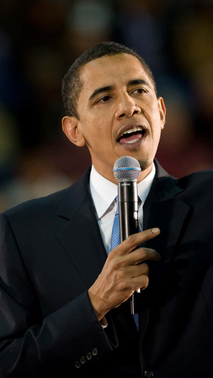 Barack Obama 桌布 壁紙 — 巴拉克·歐巴馬熱情地對著麥克風講話，身穿深色西裝和藍色領帶。