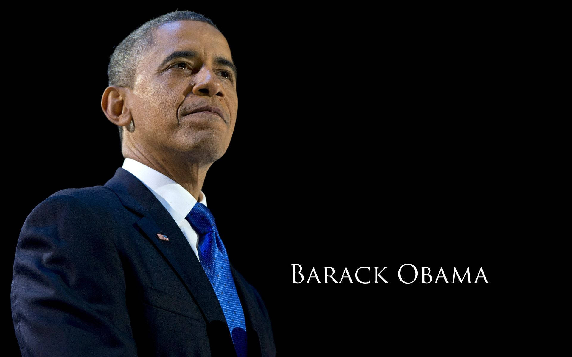 Barack 桌布 壁紙 — 巴拉克·歐巴馬穿著深色西裝和藍色領帶，站在黑色背景前，他的名字以白色文字顯示。