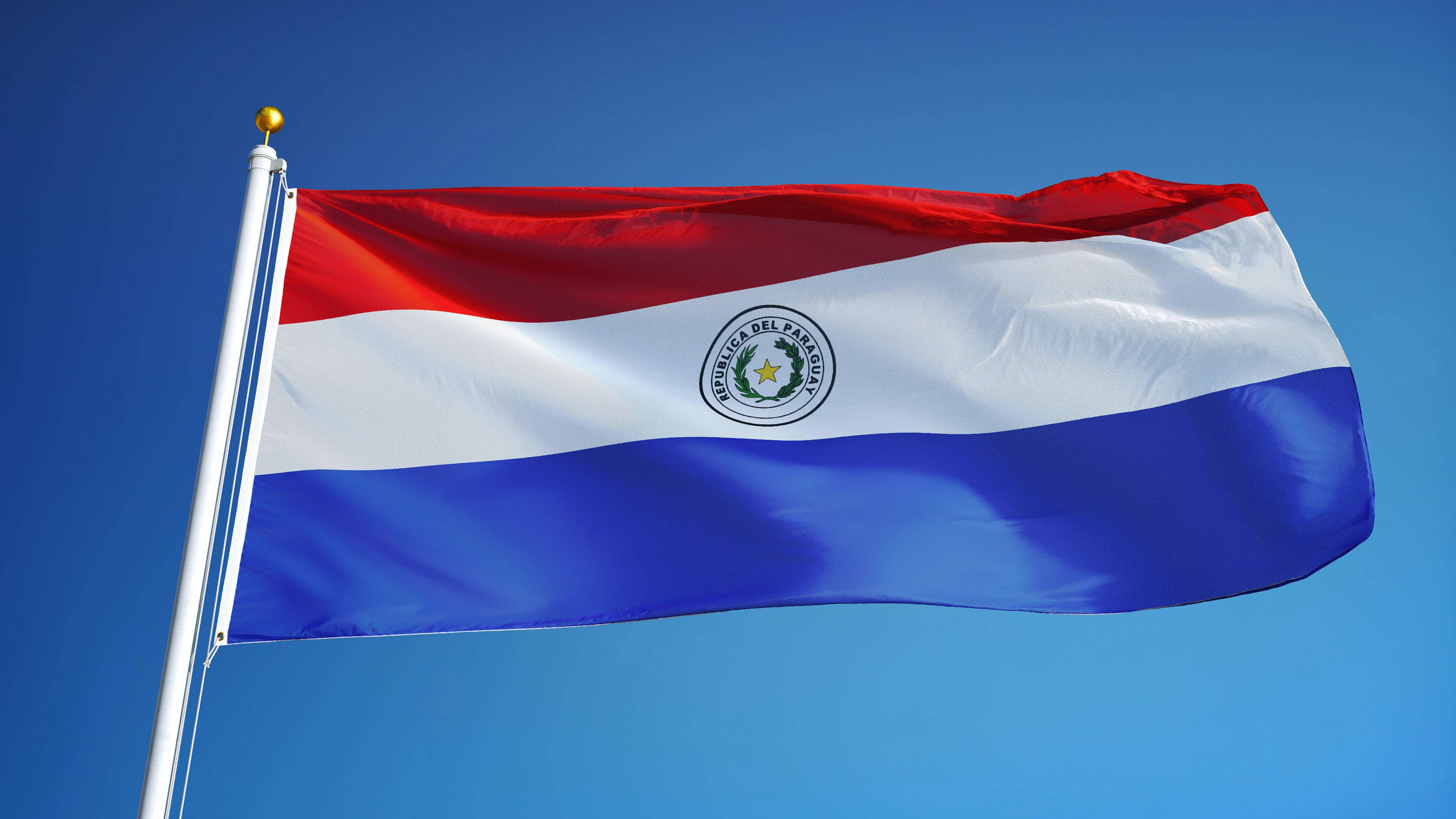 Paraguay 桌布 壁紙 — 巴拉圭國旗在清澈的藍天下自豪地飄揚，帶有鮮豔的紅、白、藍條紋。