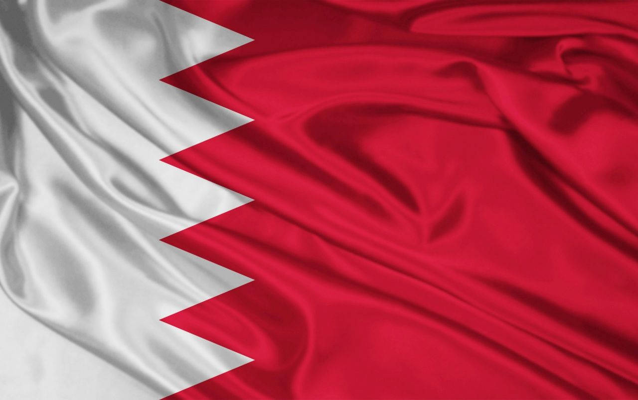 Bahrain 桌布 壁紙 — 巴林國旗的近距離特寫，旗幟飄揚，呈現豐富的紅白色彩和銳利的鋸齒邊緣。