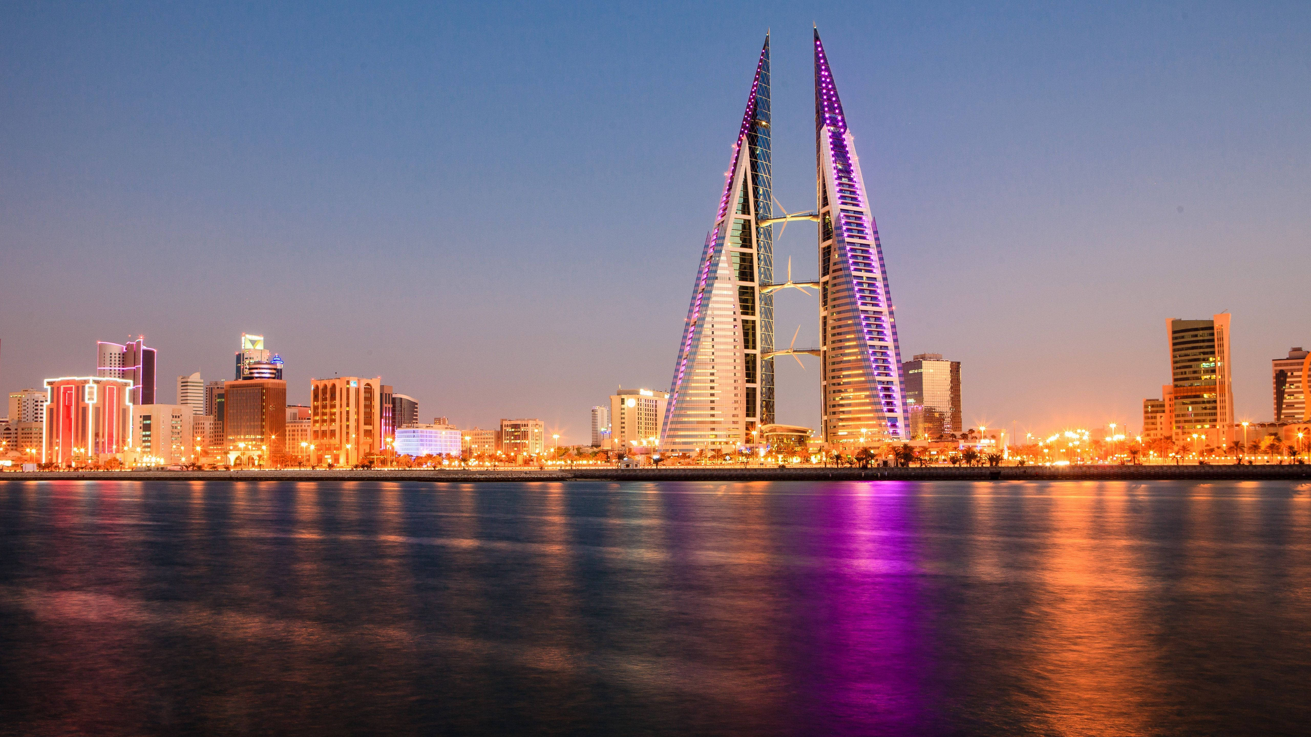 Bahrain 桌布 壁紙 — 巴林標誌性的雙子塔在暮色天空下散發紫色光芒，倒映在平靜的水面上。