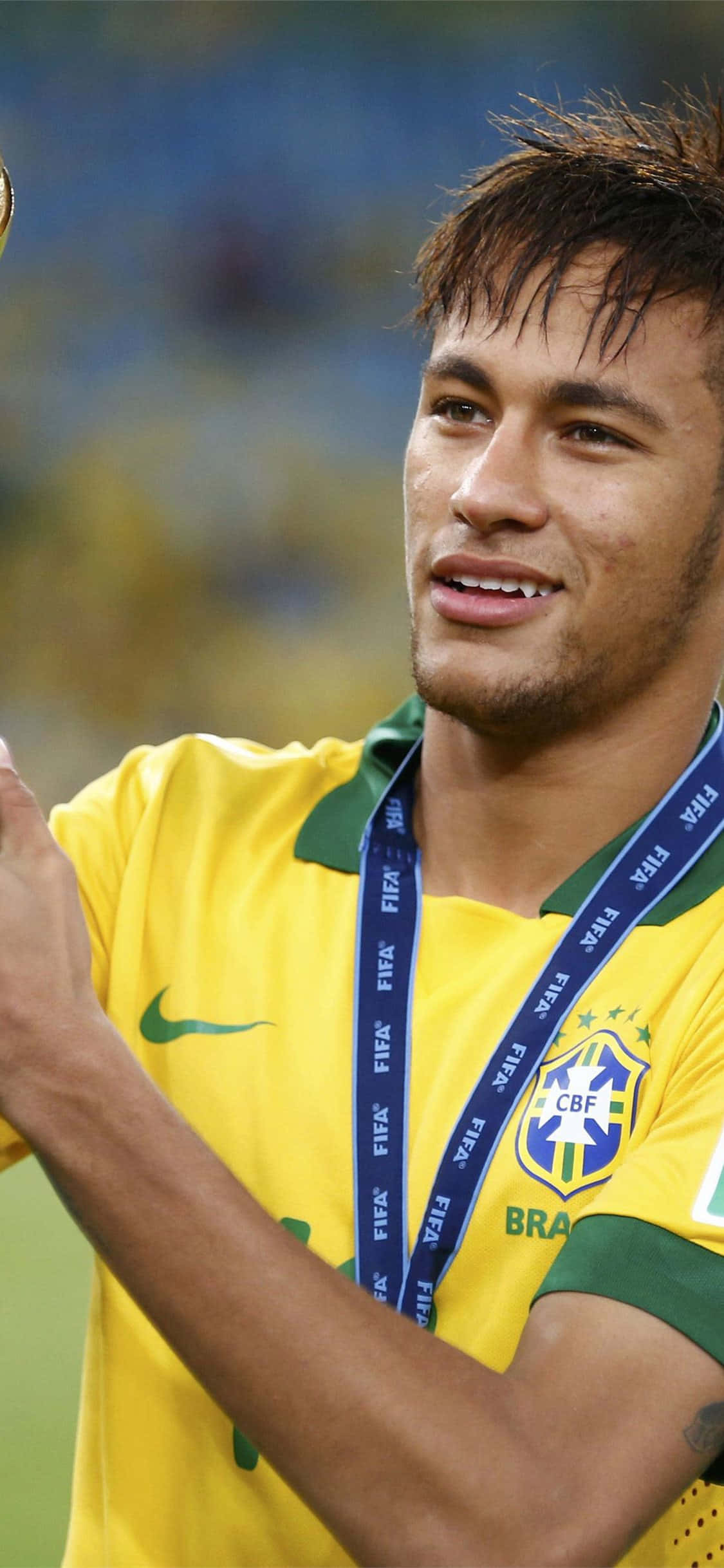 Neymar iPhone 桌布 壁紙 — 巴西足球巨星內馬爾自豪地微笑，手持獎盃，身穿黃色國家隊球衣。