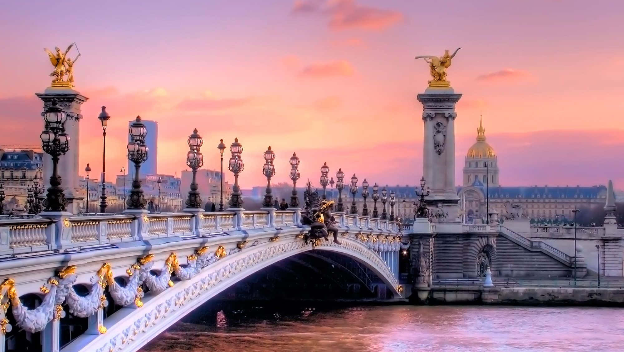 Paris Desktop 桌布 壁紙 — 巴黎亞歷山大三世橋在柔和的粉紅色和橙色日落天空下，金色雕像和華麗燈飾閃閃發光。