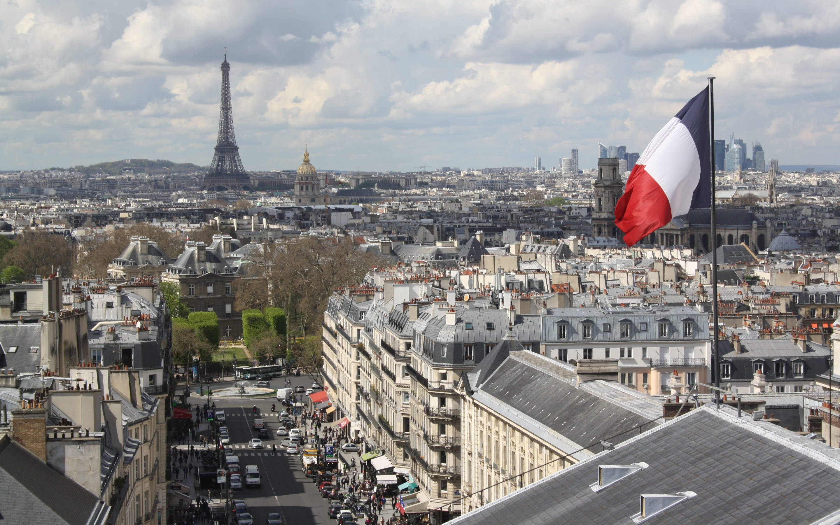 France Flag 桌布 壁紙 — 巴黎全景，展示艾菲爾鐵塔和一面在陰天飄揚的法國國旗。