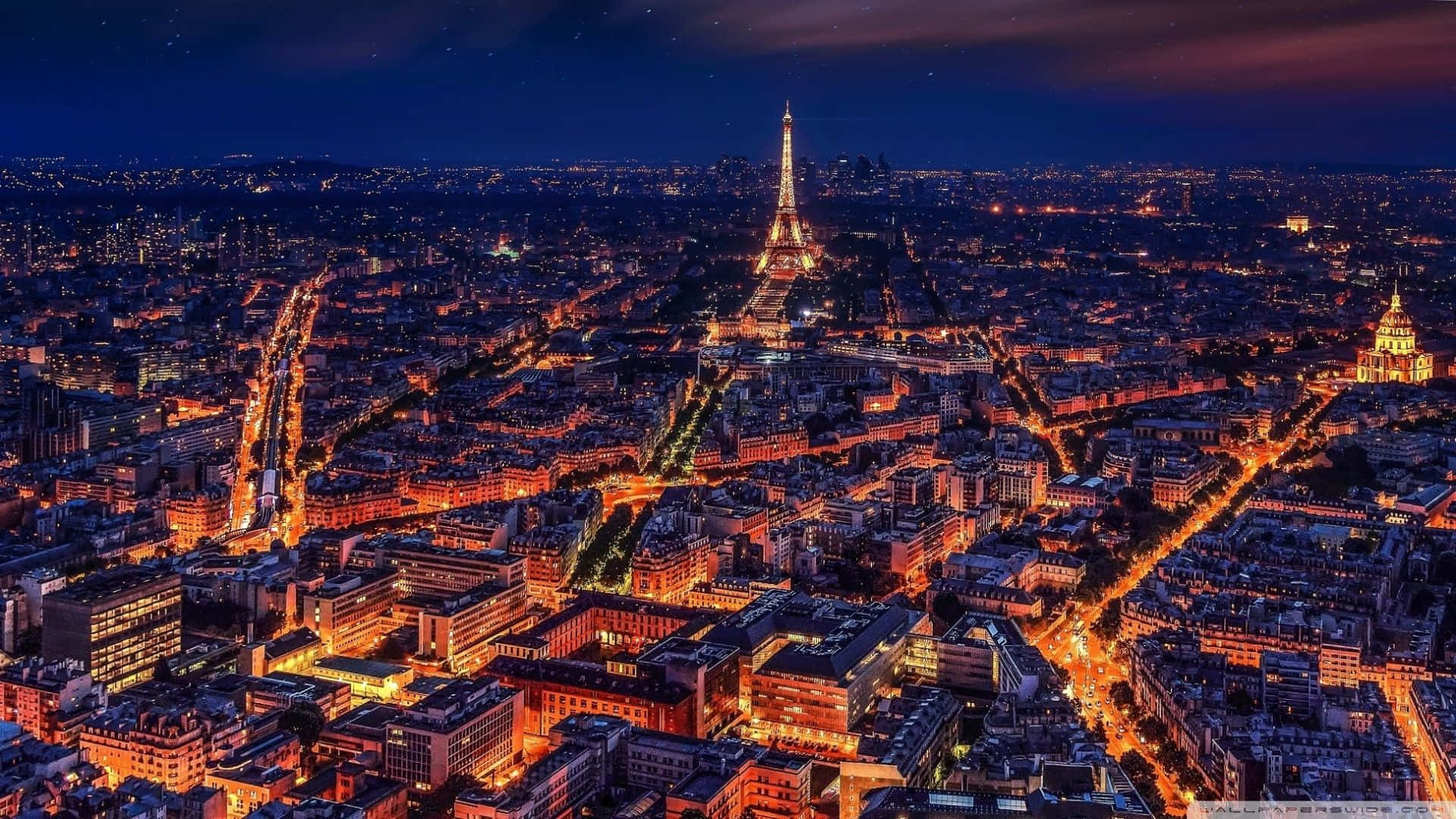 Paris At Night 桌布 壁紙 — 巴黎夜晚的鳥瞰圖，艾菲爾鐵塔在星空下溫暖的城市燈光海洋中閃耀。
