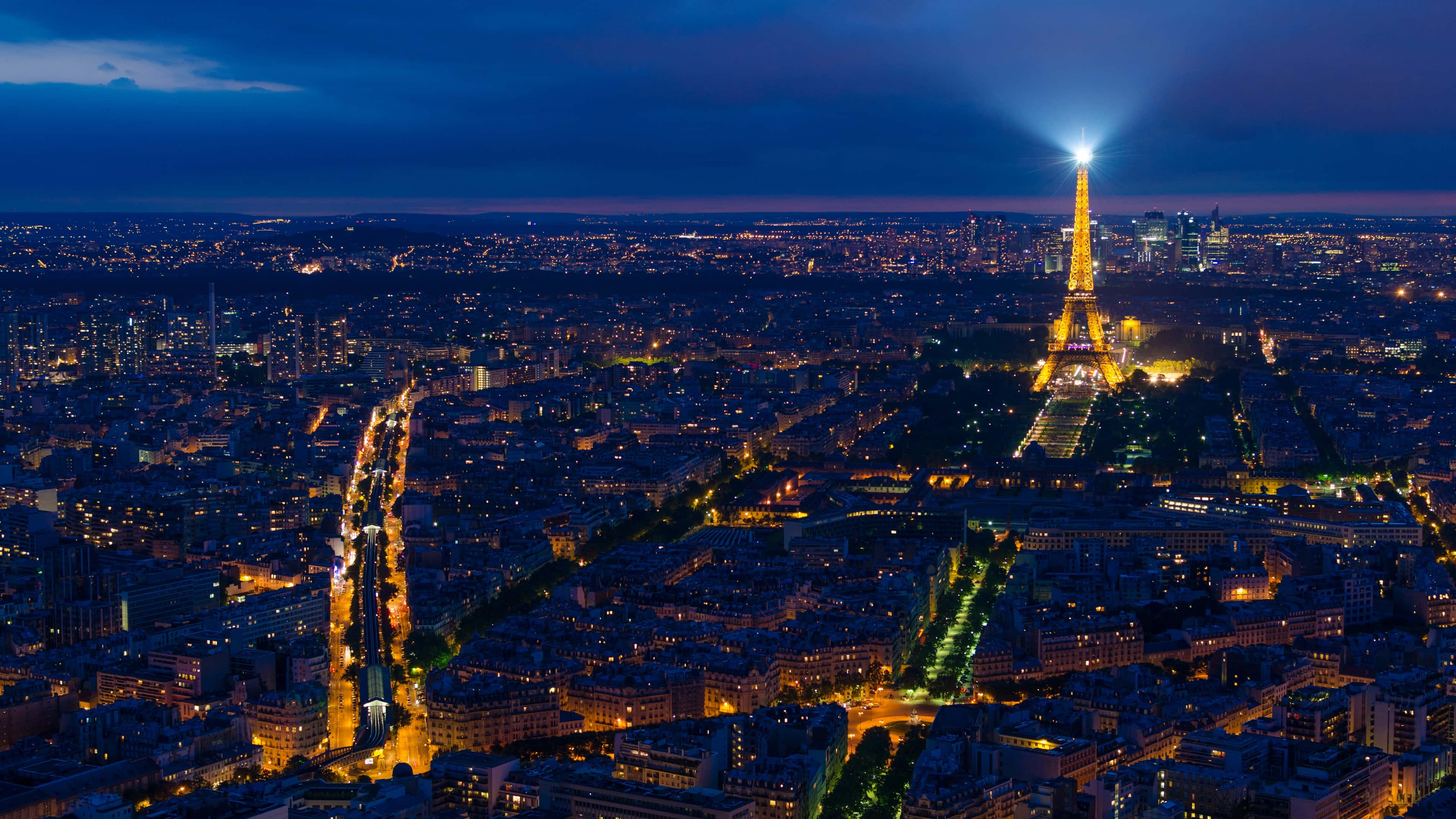 Paris At Night 桌布 壁紙 — 巴黎夜景天際線，艾菲爾鐵塔在深藍色天空中明亮閃耀。