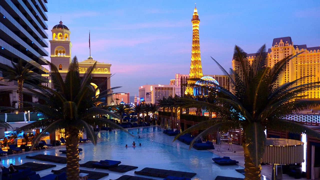 720p Las Vegas 桌布 壁紙 — 巴黎拉斯維加斯酒店充滿活力的黃昏泳池場景，發光的艾菲爾鐵塔複製品和棕櫚樹環繞著水面。
