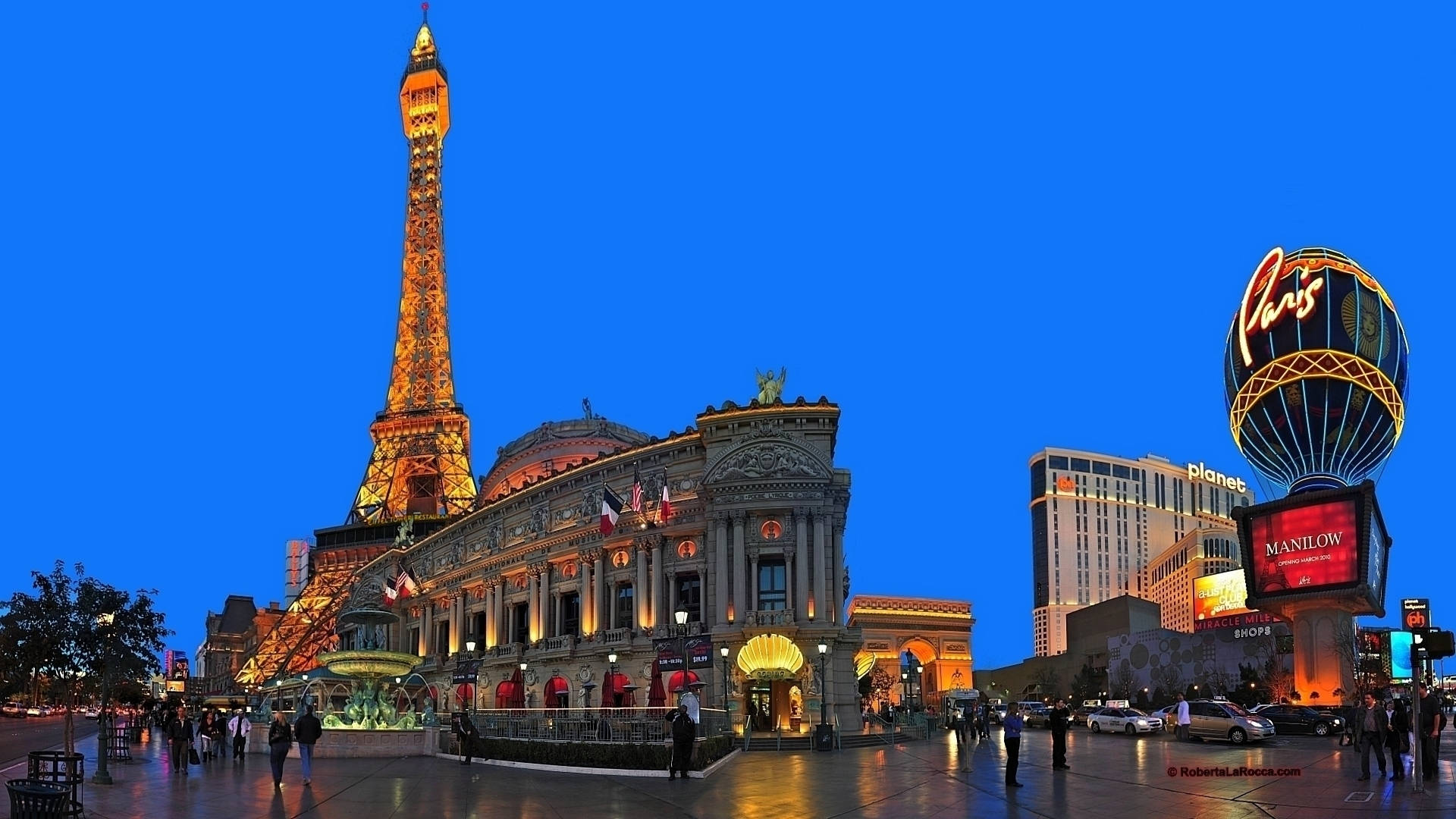 Las Vegas 桌布 壁紙 — 巴黎拉斯維加斯酒店充滿活力的黃昏場景，閃耀的艾菲爾鐵塔複製品和標誌性的巴黎酒店招牌映襯著深藍色的天空。