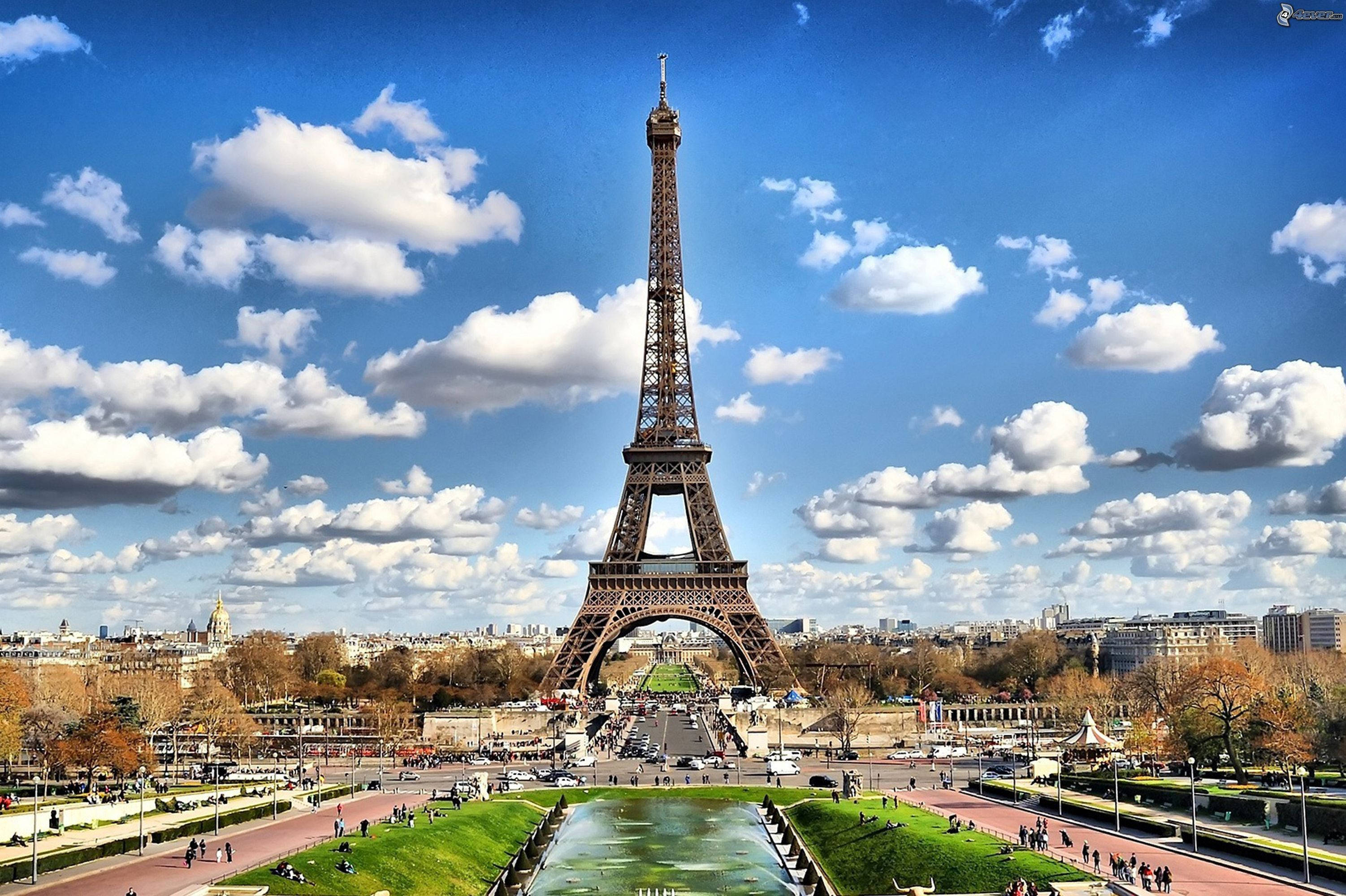 Eiffel Tower 桌布 壁紙 — 巴黎的艾菲爾鐵塔在點綴著蓬鬆白雲的鮮豔藍天下高聳入雲。
