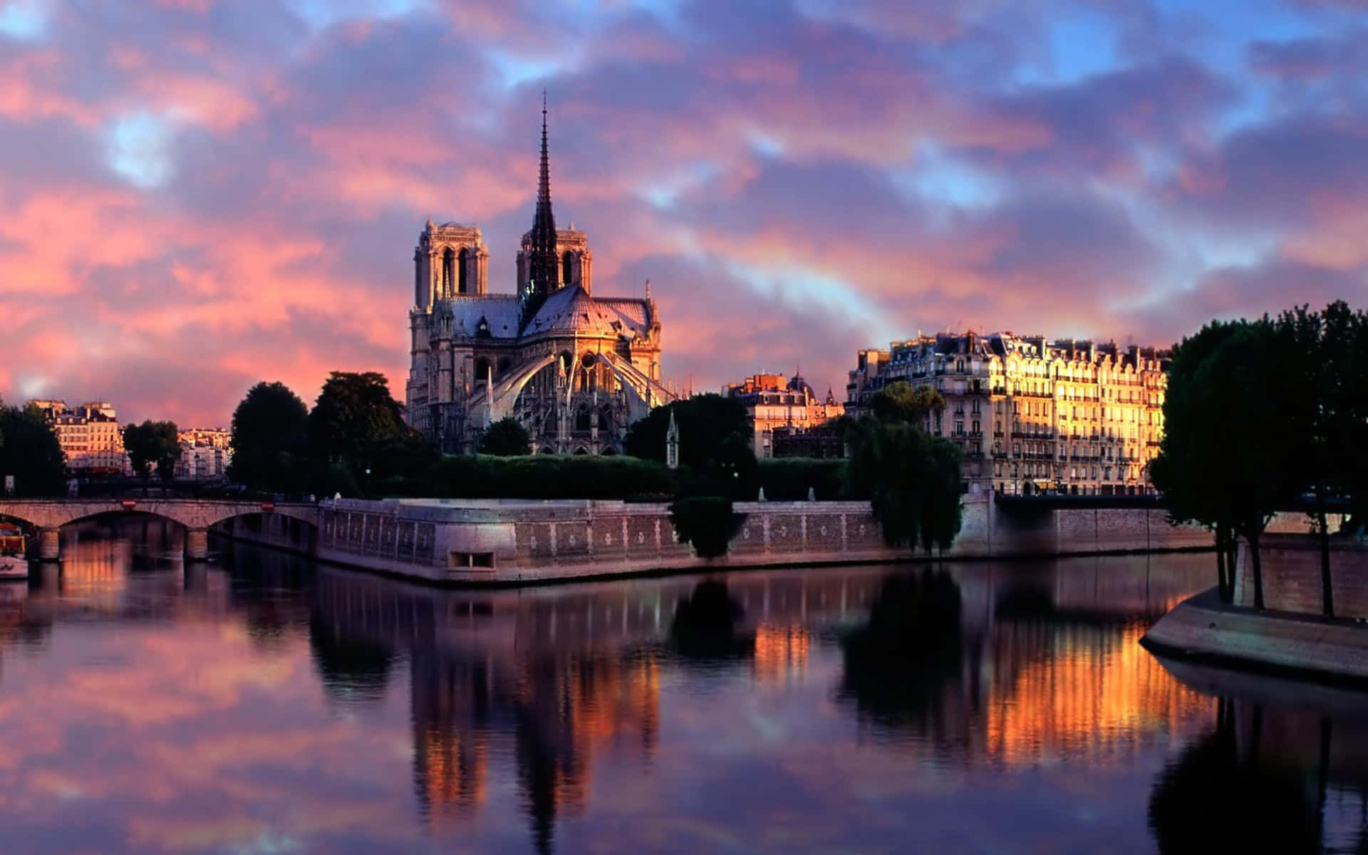 Notre Dame 桌布 壁紙 — 巴黎聖母院在充滿活力的粉紅色和紫色日落天空下倒映在塞納河中。