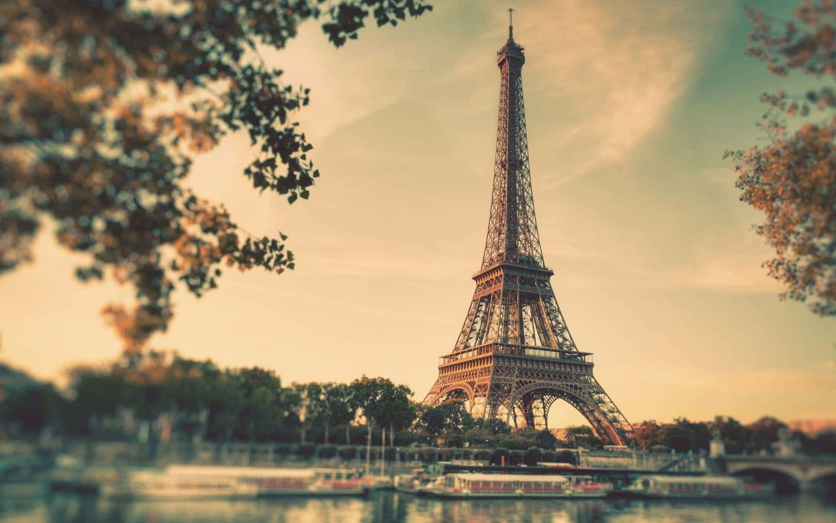 Eiffel Tower 桌布 壁紙 — 巴黎鐵塔在秋葉和寧靜河流的襯托下巍然聳立，河上有小船。