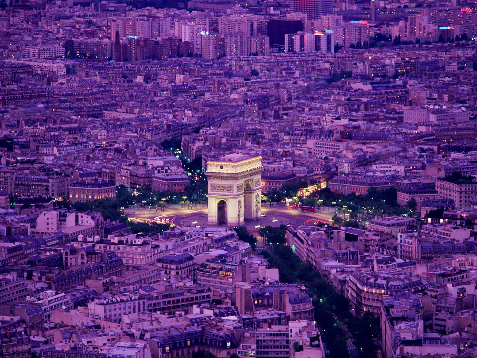 Paris Desktop 桌布 壁紙 — 巴黎黃昏時的鳥瞰圖，凱旋門在紫色暮光下閃耀，下方是密集的城市屋頂。