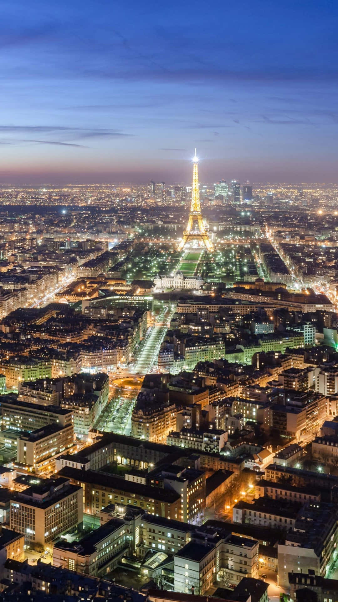 Paris At Night 桌布 壁紙 — 巴黎黃昏時的鳥瞰圖，艾菲爾鐵塔在燈火通明的城市景觀上方閃耀著光芒。