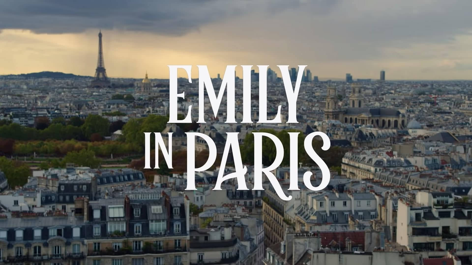 艾蜜莉在巴黎 桌布 壁紙 — 巴黎黃昏的空中景觀，艾菲爾鐵塔和「EMILY IN PARIS」文字疊加在城市景觀上。