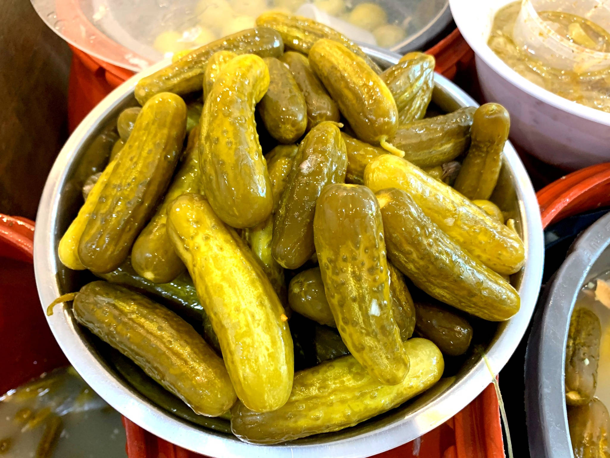 醃黃瓜 桌布 壁紙 — 市場攤位上金屬碗中高高堆起的光澤蒔蘿泡菜特寫。