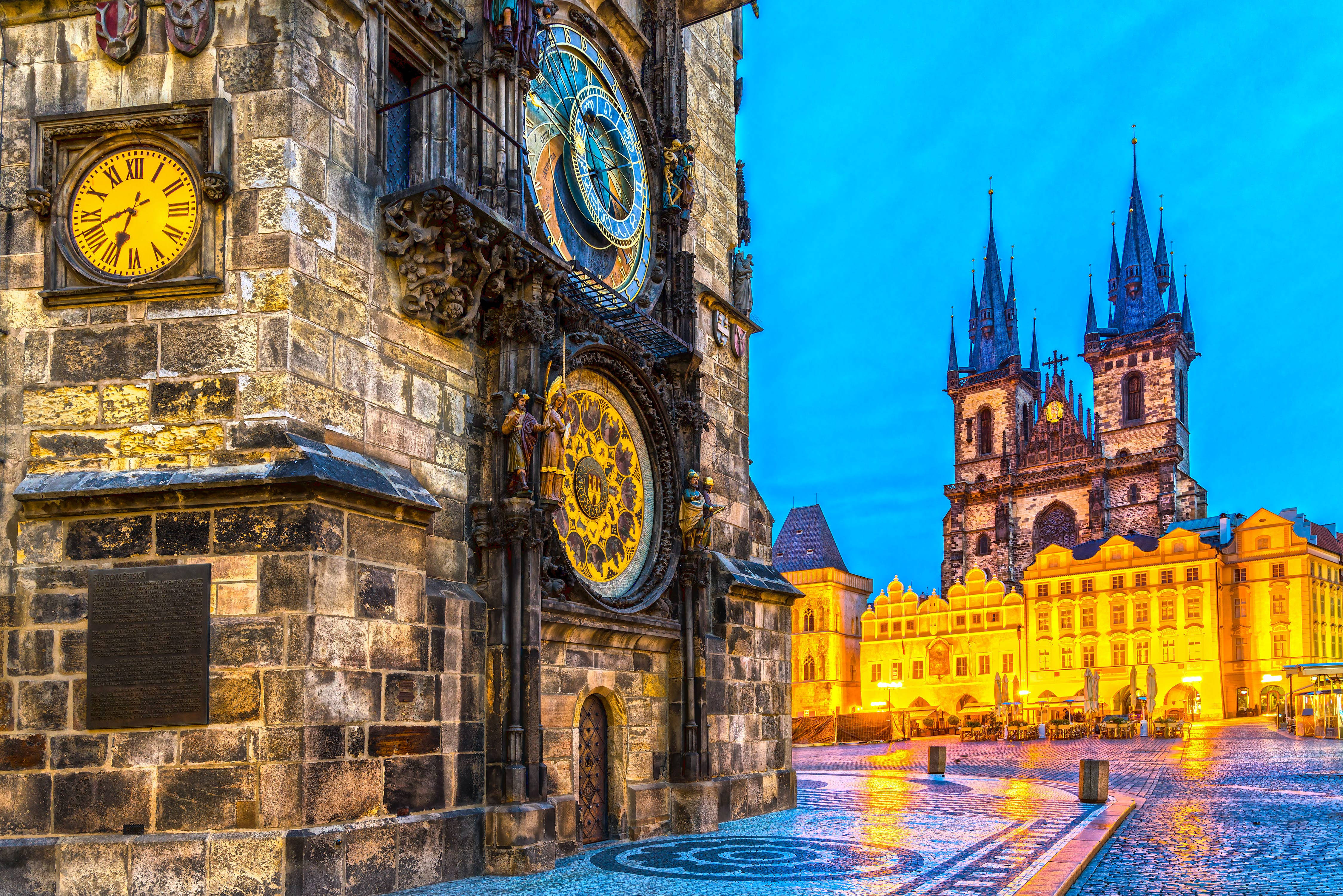Europe 桌布 壁紙 — 布拉格充滿活力的黃昏場景，華麗的天文鐘和哥德式教堂的金色燈光在濕漉漉的鵝卵石上反射。