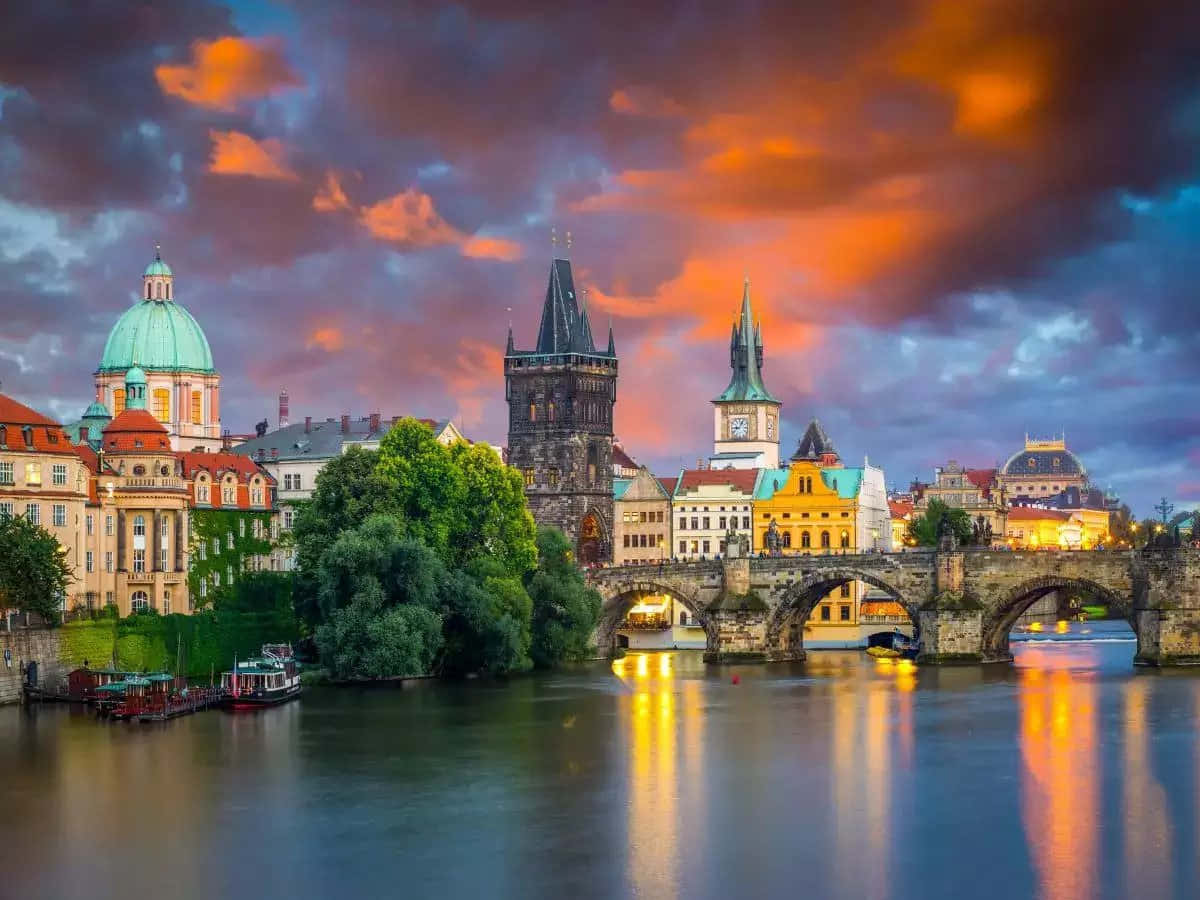 Europe 桌布 壁紙 — 布拉格查理大橋上壯麗的日落，歷史建築與閃爍燈光倒映在伏爾塔瓦河中。