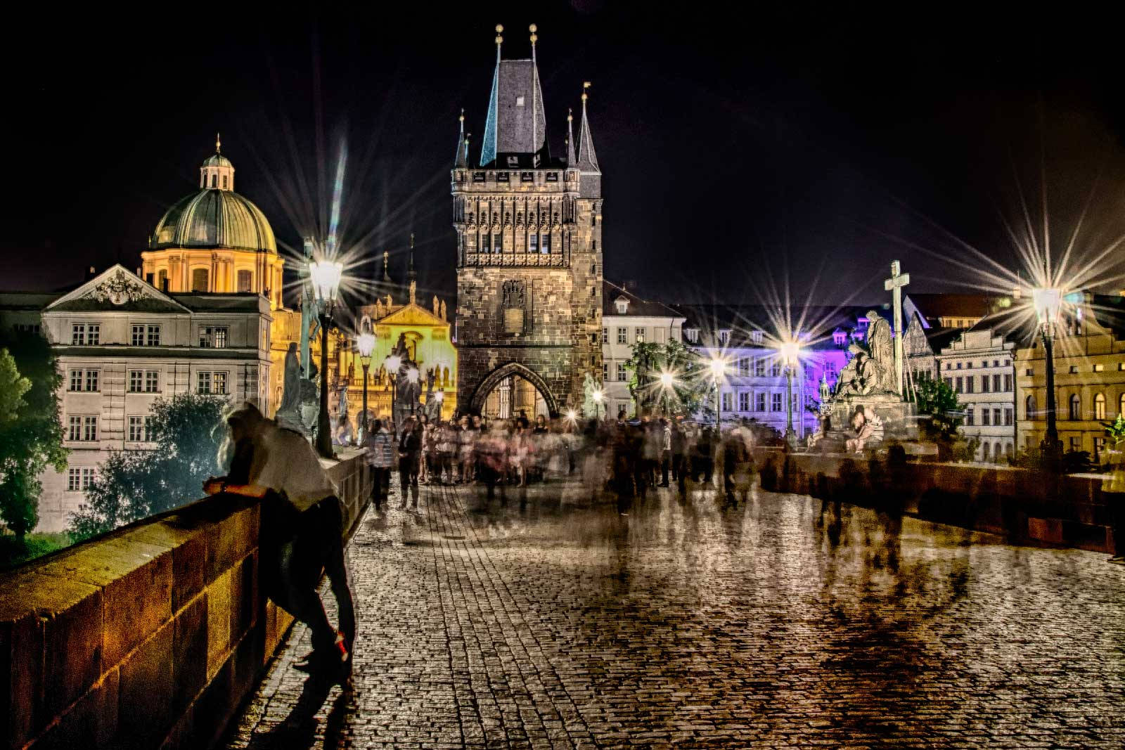 Europe 桌布 壁紙 — 布拉格查理大橋的長時間曝光夜景，潮濕的鵝卵石上閃爍著街燈和模糊的行人。