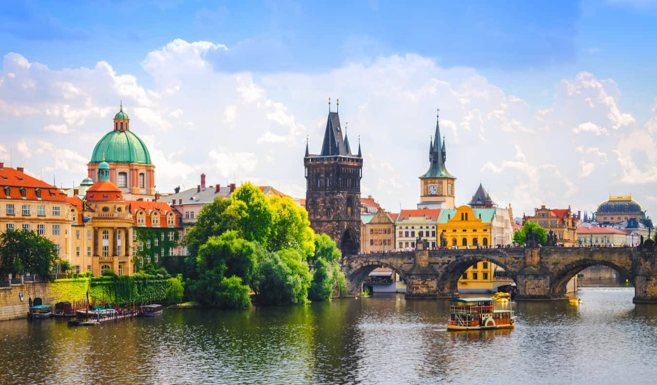 Europe 桌布 壁紙 — 布拉格的查理大橋橫跨平靜的河流，上方是點綴著蓬鬆雲朵的明亮藍天。