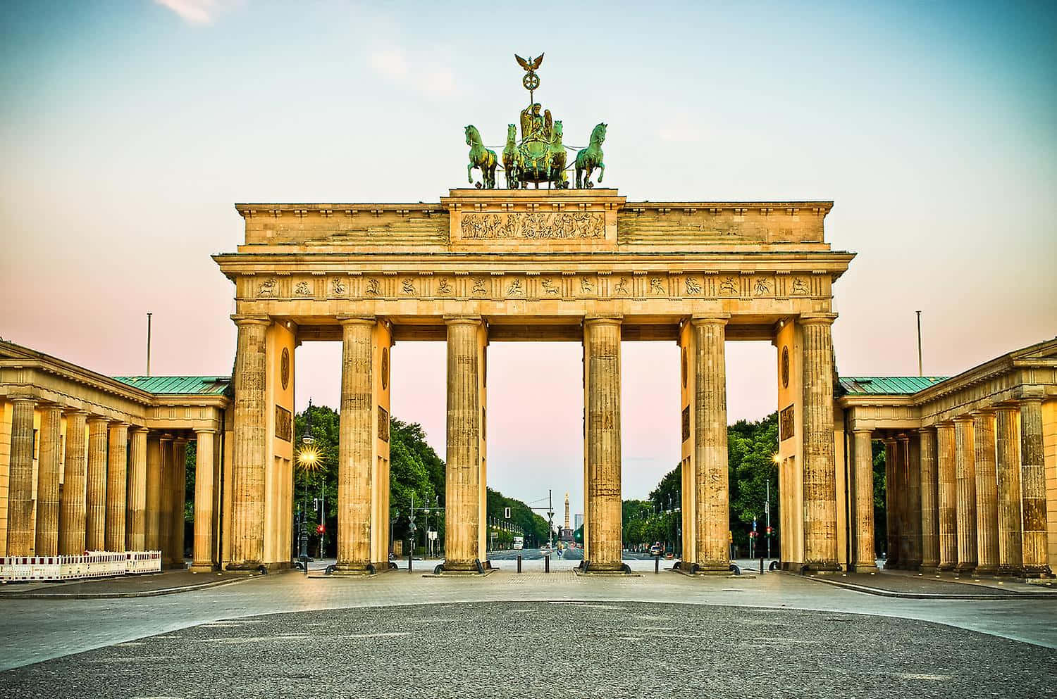 Berlin 桌布 壁紙 — 布蘭登堡門在日落時分巍然聳立，溫暖的金色光芒沐浴著其新古典主義柱廊和頂端的四馬戰車雕像。