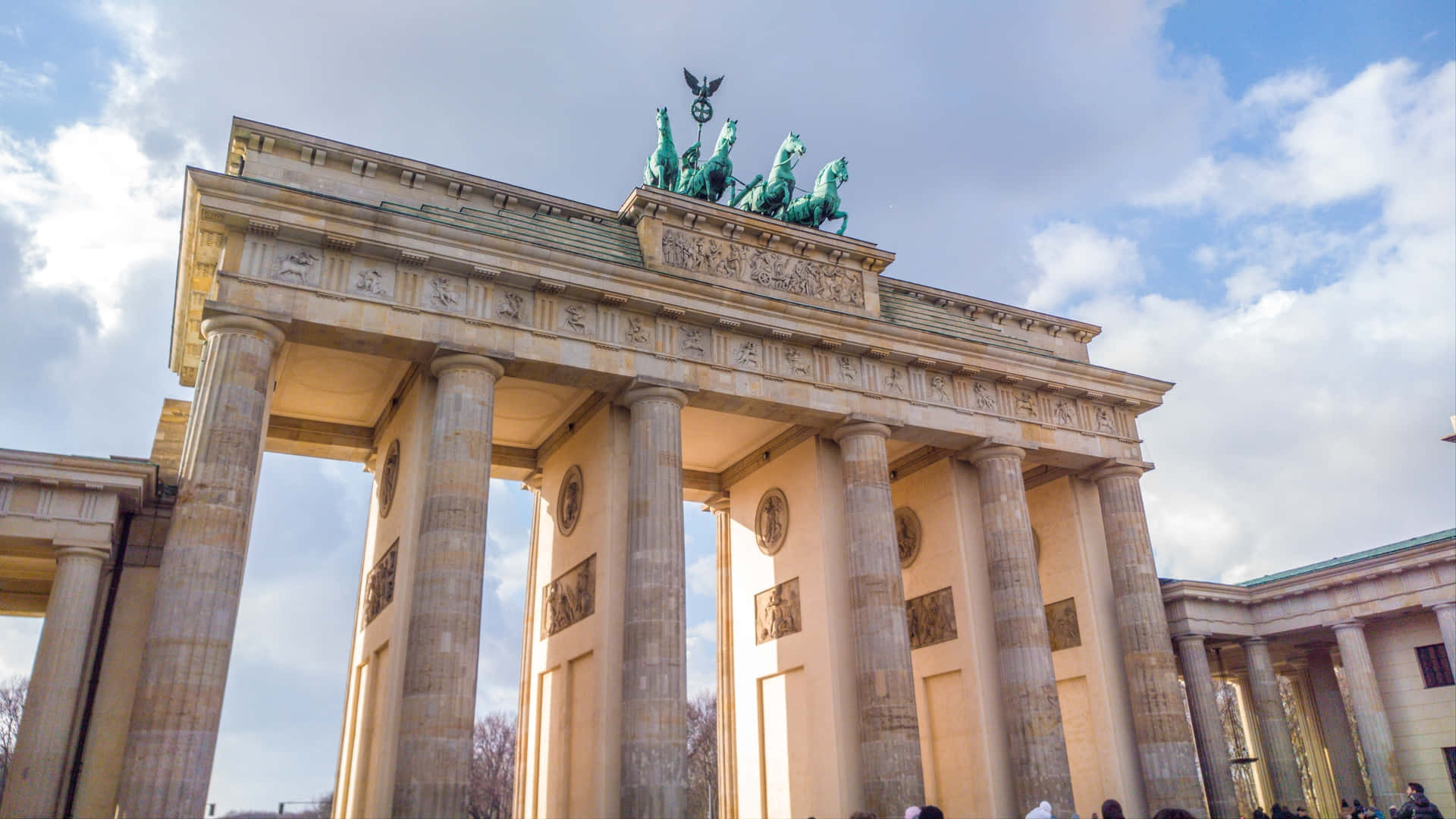 Berlin 桌布 壁紙 — 布蘭登堡門在部分多雲的天空下巍然聳立，其標誌性的四馬戰車雕像在新古典主義建築頂部閃耀。