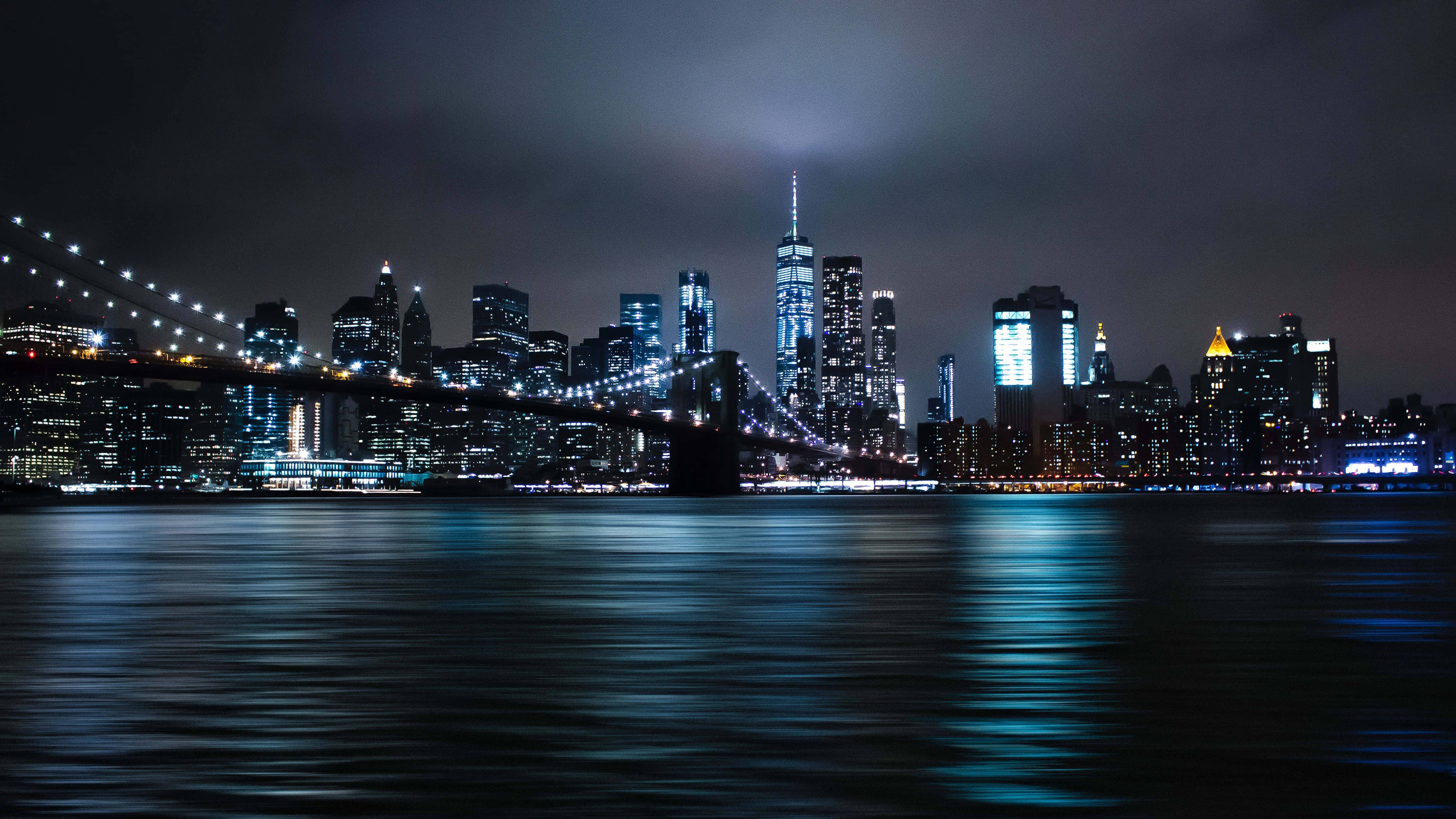 Brooklyn Bridge 桌布 壁紙 — 布魯克林大橋和曼哈頓天際線的壯麗夜景，閃爍的摩天大樓倒映在黑暗的水面上。