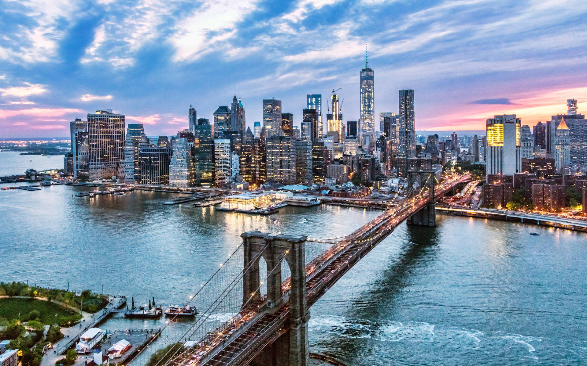 New York Skyline 桌布 壁紙 — 布魯克林大橋在日落時橫跨河流，背後是閃閃發光的紐約市天際線。