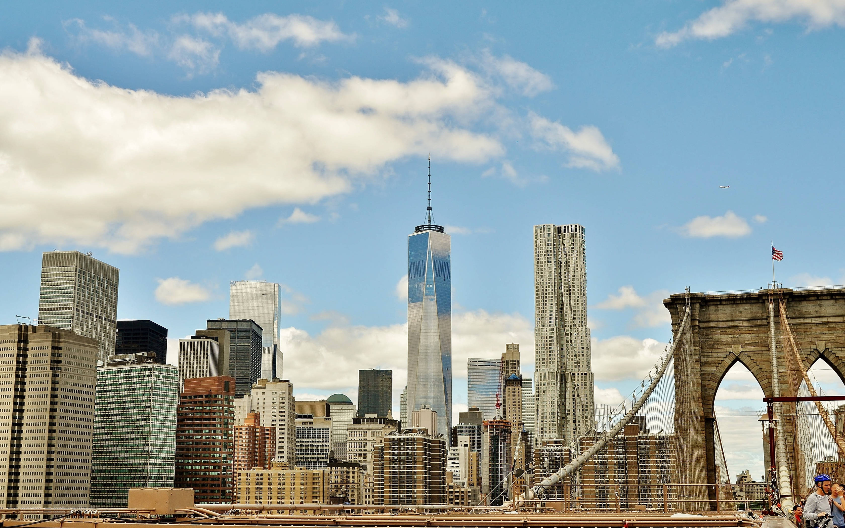Brooklyn Bridge 桌布 壁紙 — 布魯克林大橋在晴朗的日子裡延伸，世界貿易中心一號大樓聳立在紐約市的天際線上，藍天白雲。