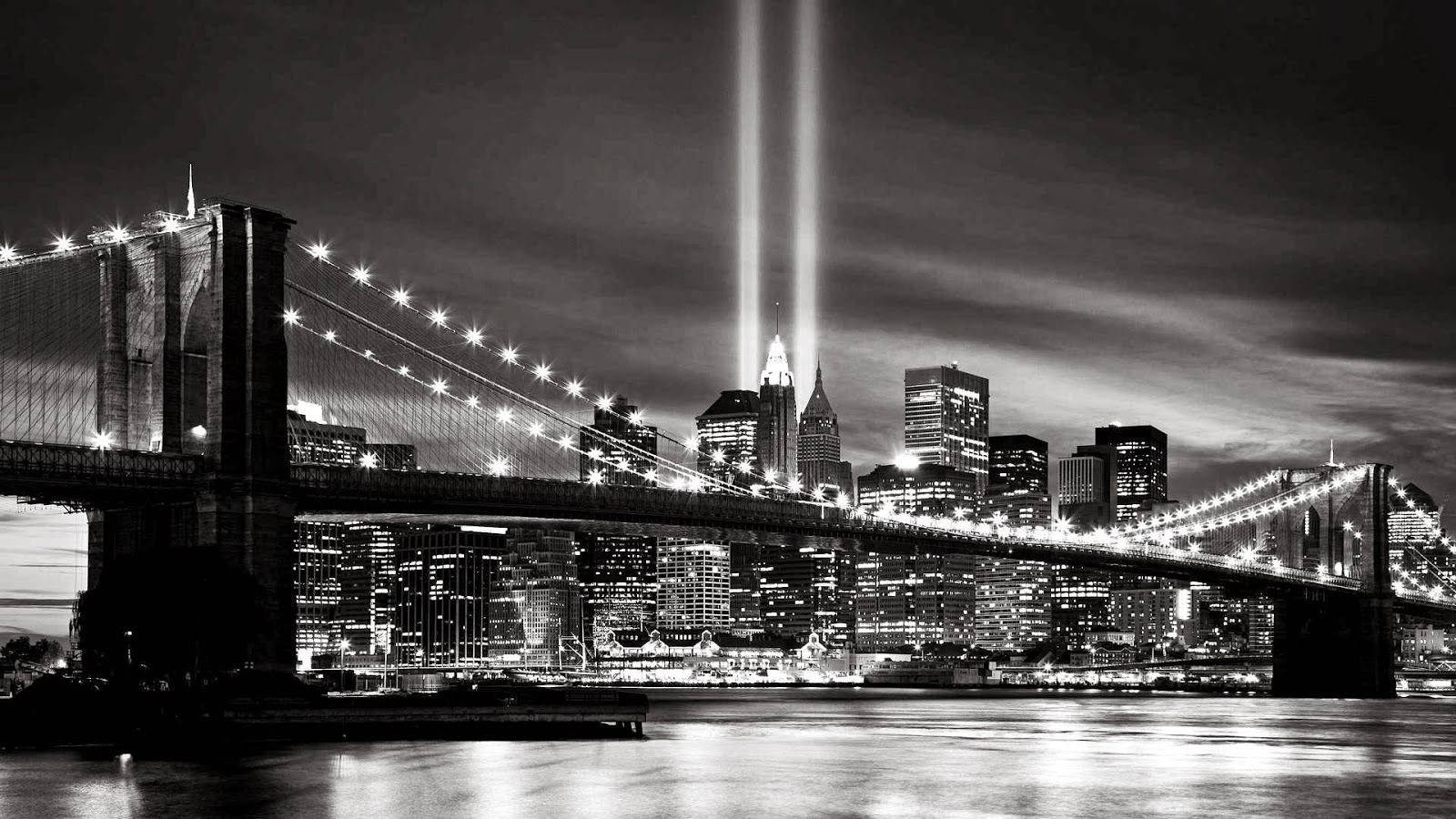New York 桌布 壁紙 — 布魯克林大橋橫跨一條黑暗的河流，下方是黑白紐約市天際線，兩道垂直光束刺穿夜空。