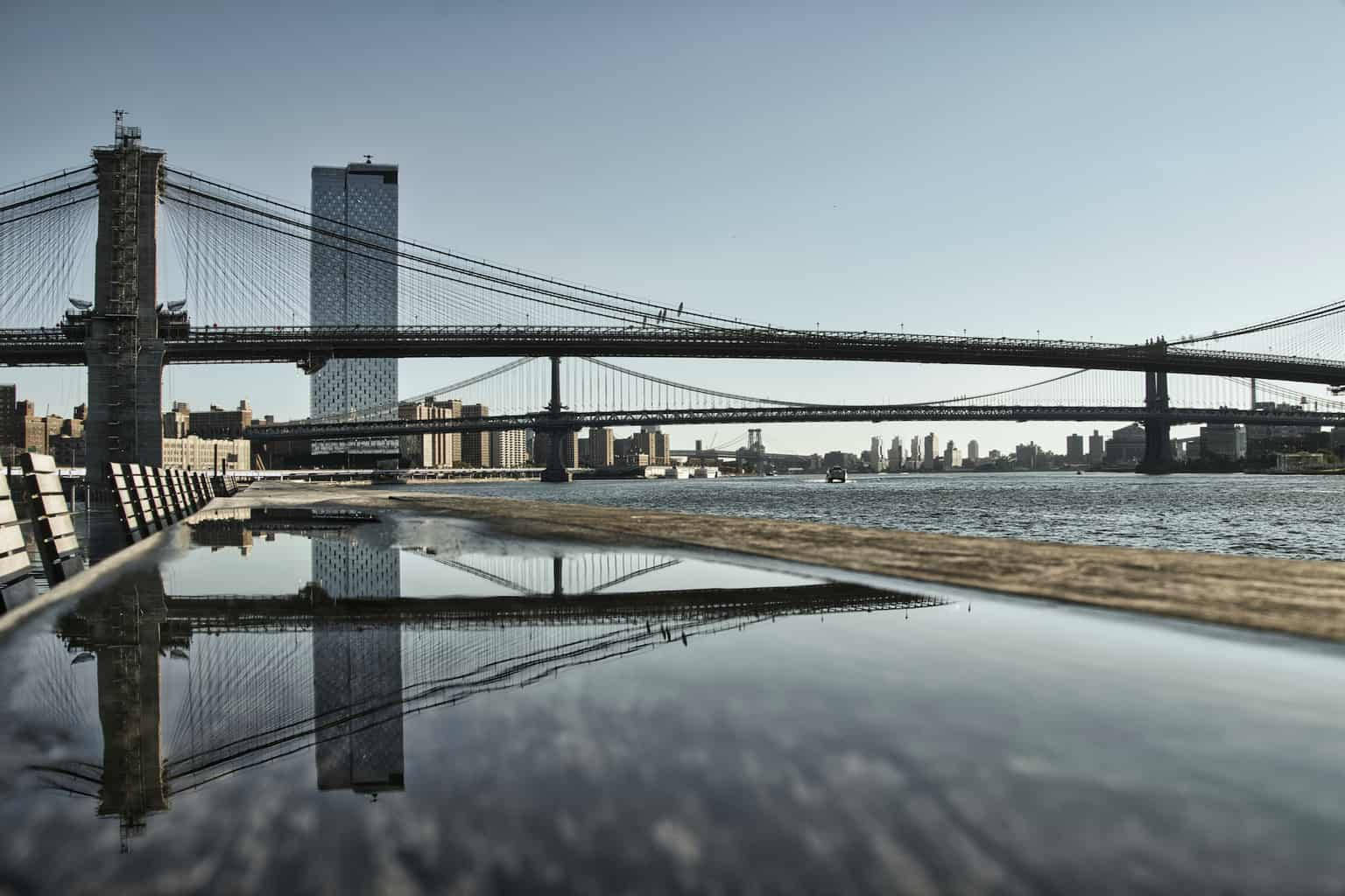 New York 桌布 壁紙 — 布魯克林大橋橫跨東河，其倒影映照在清澈藍天下的一個水坑中。