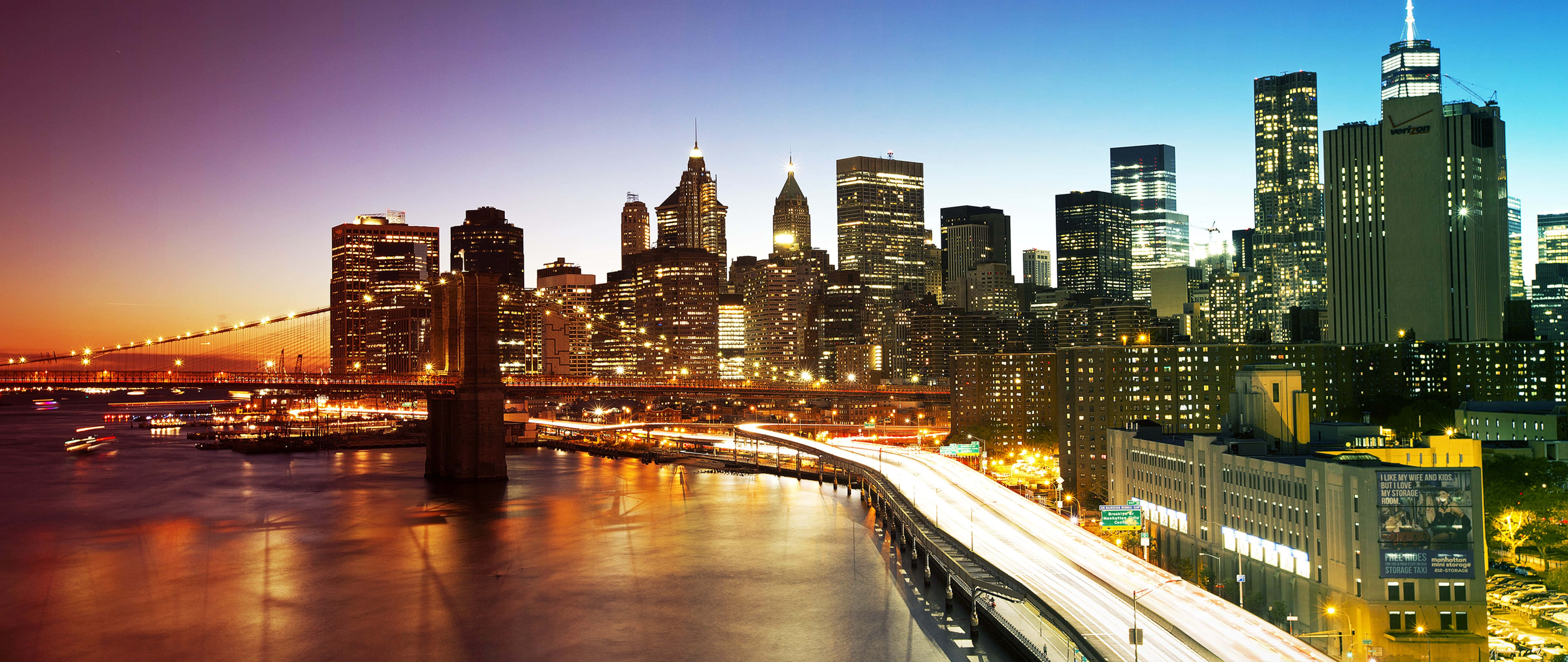 New York City 4K Ultra HD 桌布 壁紙 — 布魯克林大橋橫跨發光的河流，城市燈光在暮色天空下的水面上反射。