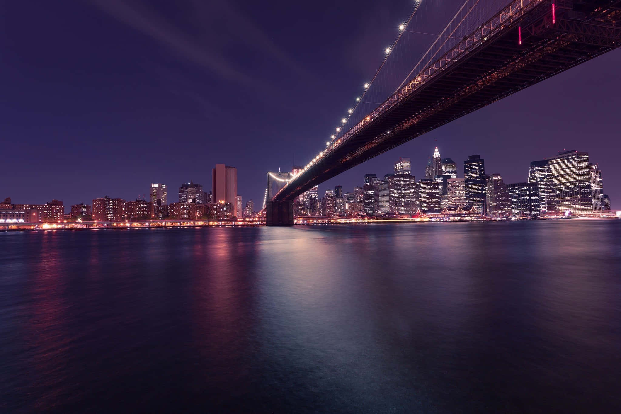 City Desktop 桌布 壁紙 — 布魯克林大橋的壯麗夜景，橋上的燈光在平靜的水面上反射，映襯著充滿活力的城市天際線。