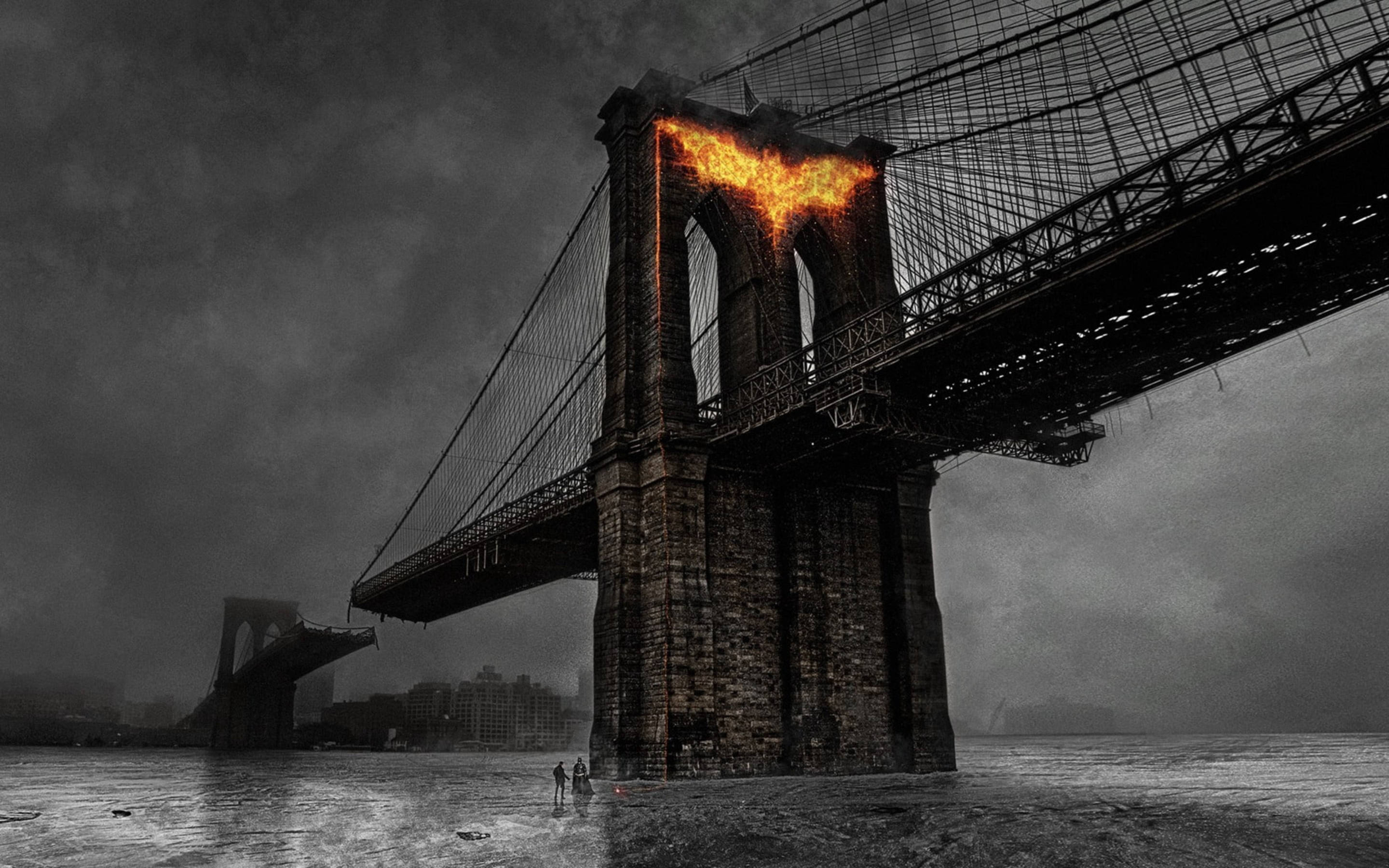 Batman Logo 桌布 壁紙 — 布魯克林大橋的戲劇性黑白景觀，其塔樓在暴風雨的天空下被熾熱的橙色火焰吞噬。