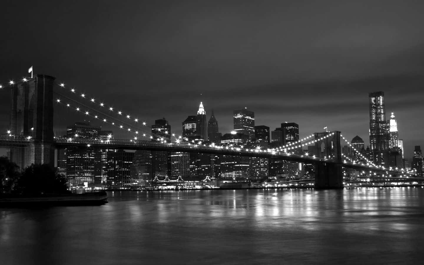 Black And White Cityscape 桌布 壁紙 — 布魯克林大橋的黑白夜景，城市燈光倒映在水面上。