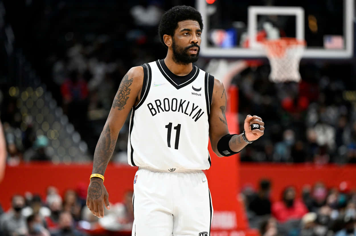 Kyrie Irving Nets 桌布 壁紙 — 布魯克林籃網球員凱里·厄文身穿白色11號球衣，站在籃球場上，專注地抱著球。