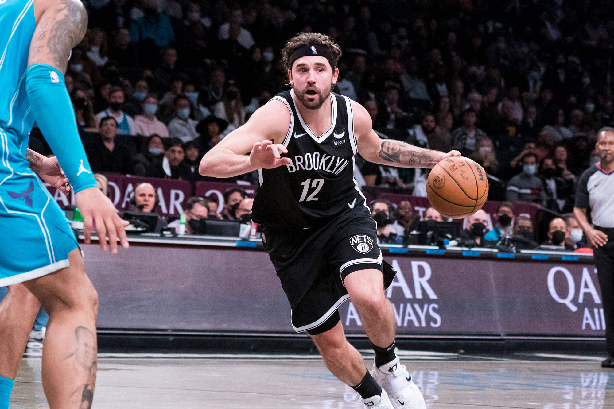 joe harris 桌布 壁紙 — 布魯克林籃網球員在明亮的場館燈光下，於擁擠的室內比賽中專注地運球。