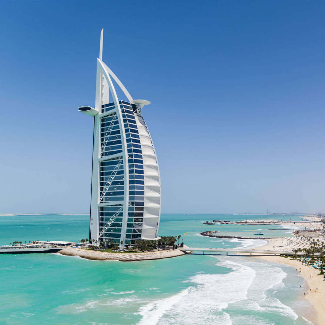 海灘 桌布 壁紙 — 帆船形的帆船酒店（Burj Al Arab Jumeirah）雄偉地矗立在人工島上，在清澈的藍天下映襯著碧綠的海水。