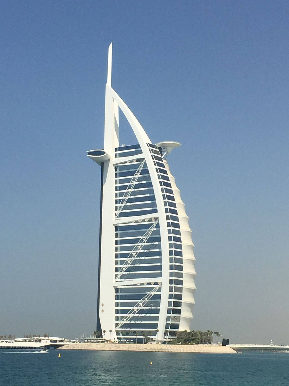 鎖屏 桌布 壁紙 — 帆船造型的帆船飯店（Burj Al Arab Jumeirah）高聳在清澈的藍天下，下方是平靜的藍綠色海水。