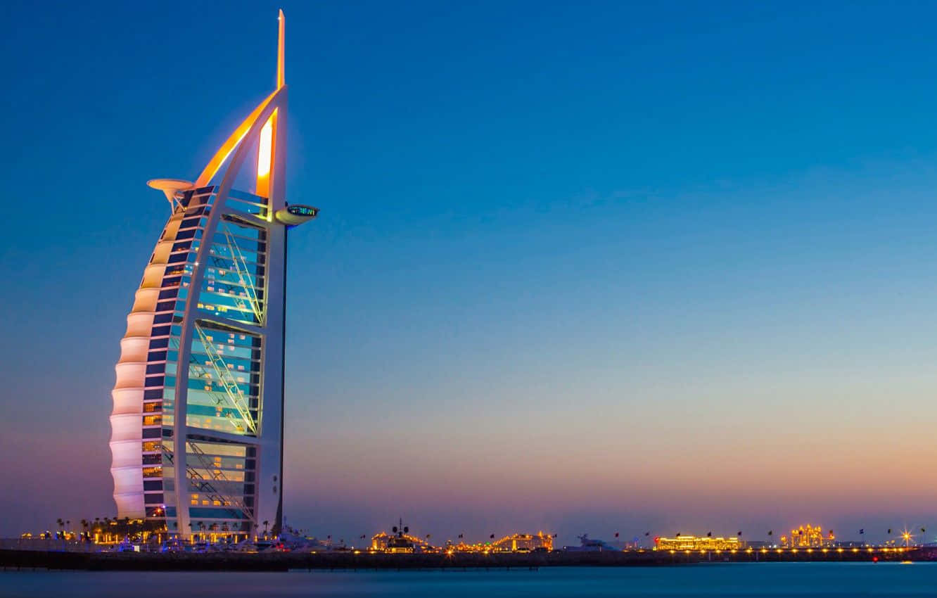 Uae 桌布 壁紙 — 帆船酒店在杜拜水域上空的暮色中散發溫暖的光芒。