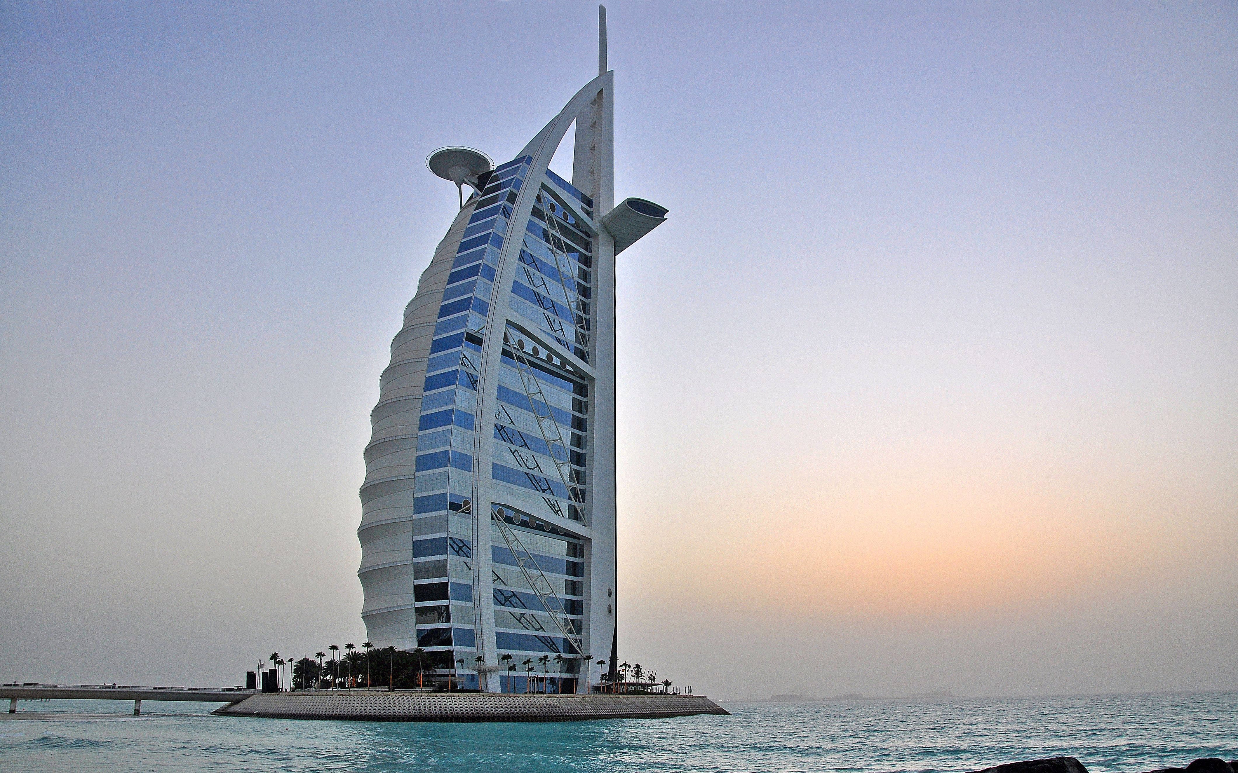 Arab 桌布 壁紙 — 帆船酒店在柔和的日落天空下高聳矗立，下方是平靜的藍綠色海水。