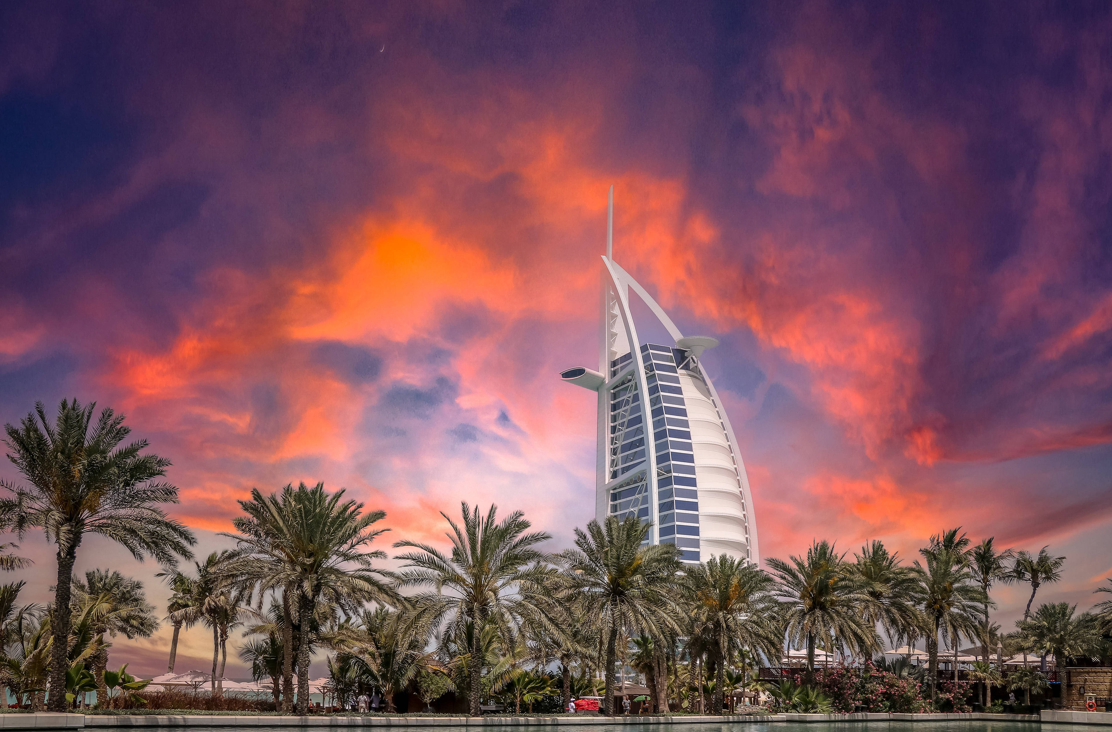Arab 桌布 壁紙 — 帆船酒店在火紅的日落天空下高聳矗立，前景有棕櫚樹。