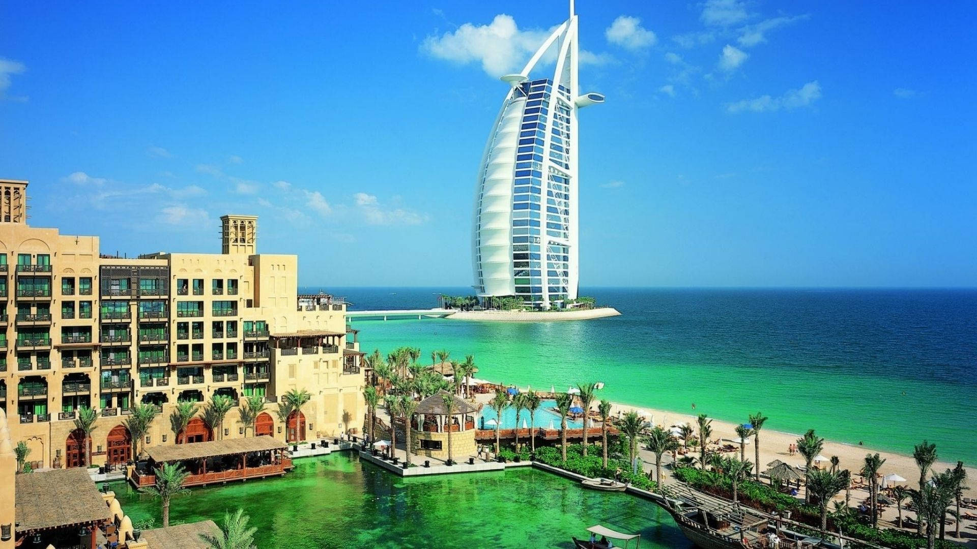 Dubai 桌布 壁紙 — 帆船酒店聳立在清澈的藍天下，俯瞰著碧綠的海水和棕櫚樹成行的海灘。