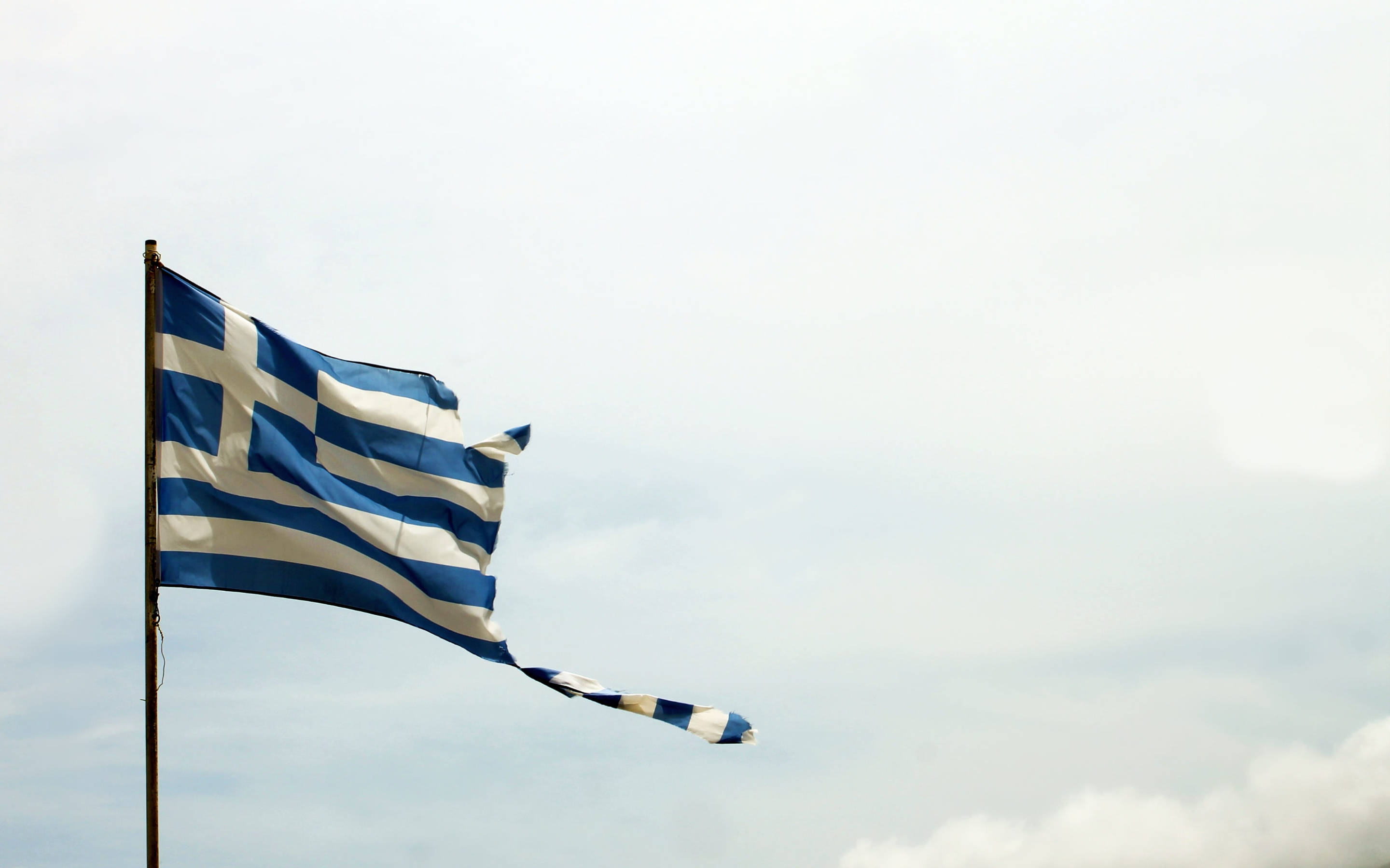 greek 桌布 壁紙 — 希臘國旗，藍白條紋和十字架，在陰天中隨風飄揚。