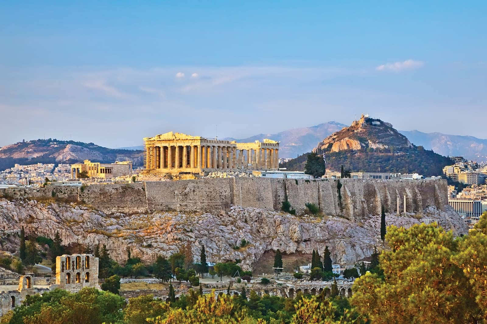 greek 桌布 壁紙 — 帕德嫩神廟雄偉地矗立在雅典衛城頂端，在清澈的藍天下，遠山和下方茂密的綠樹盡收眼底。